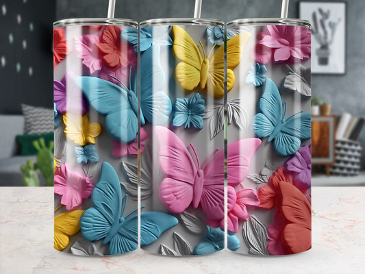Three tumblers with colorful butterflies and floral designs on a light surface.