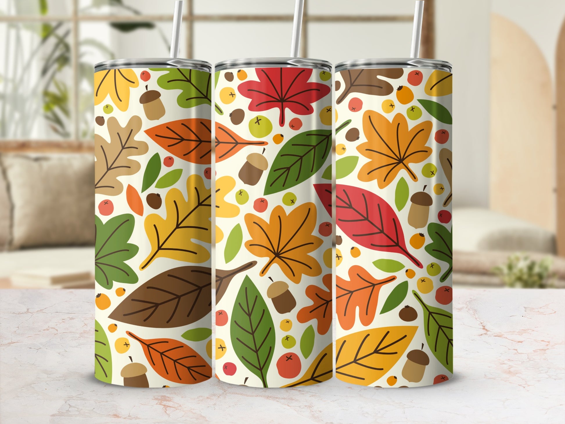 Autumn leaves and acorns pattern on three tumblers with straws.