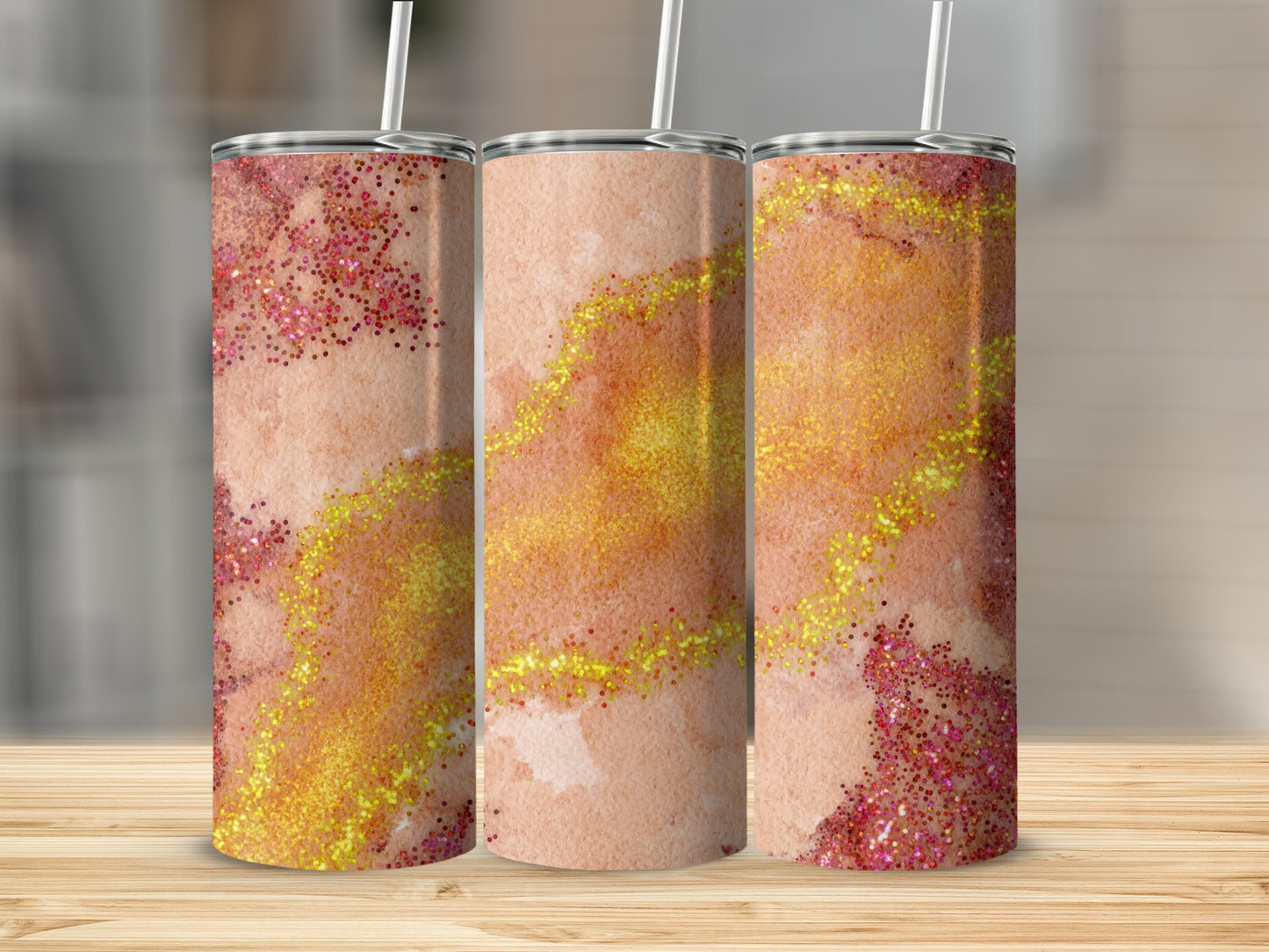 Three tumblers with a watercolor and glitter design in shades of peach and gold.