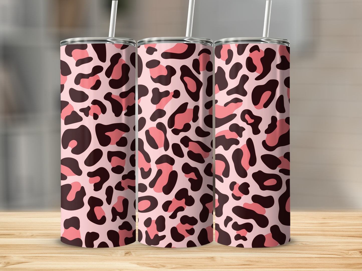 Three sleek tumblers patterned with pink and brown leopard print stand on a wooden surface.