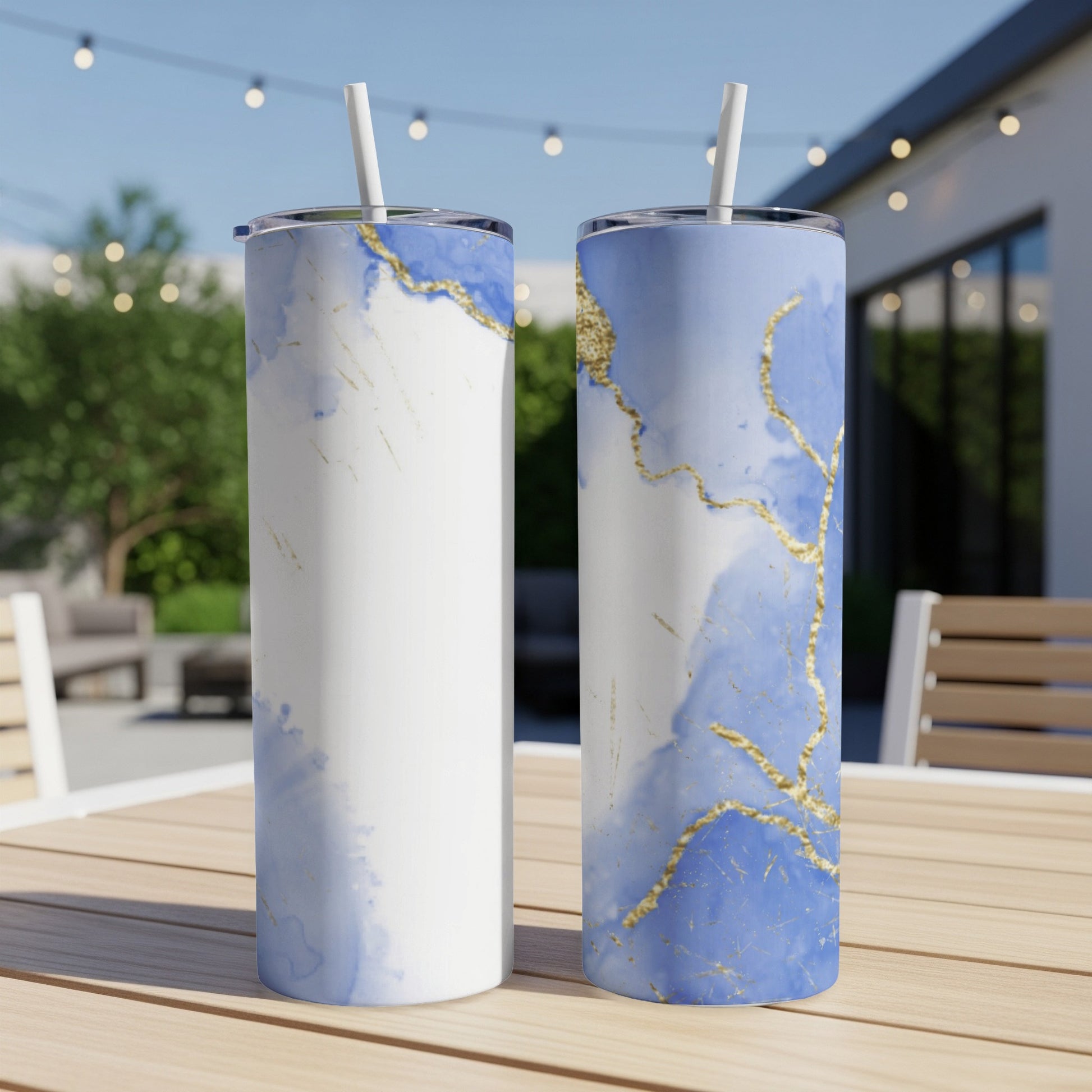 Two tall tumblers with blue watercolor and gold marble design on wooden table.