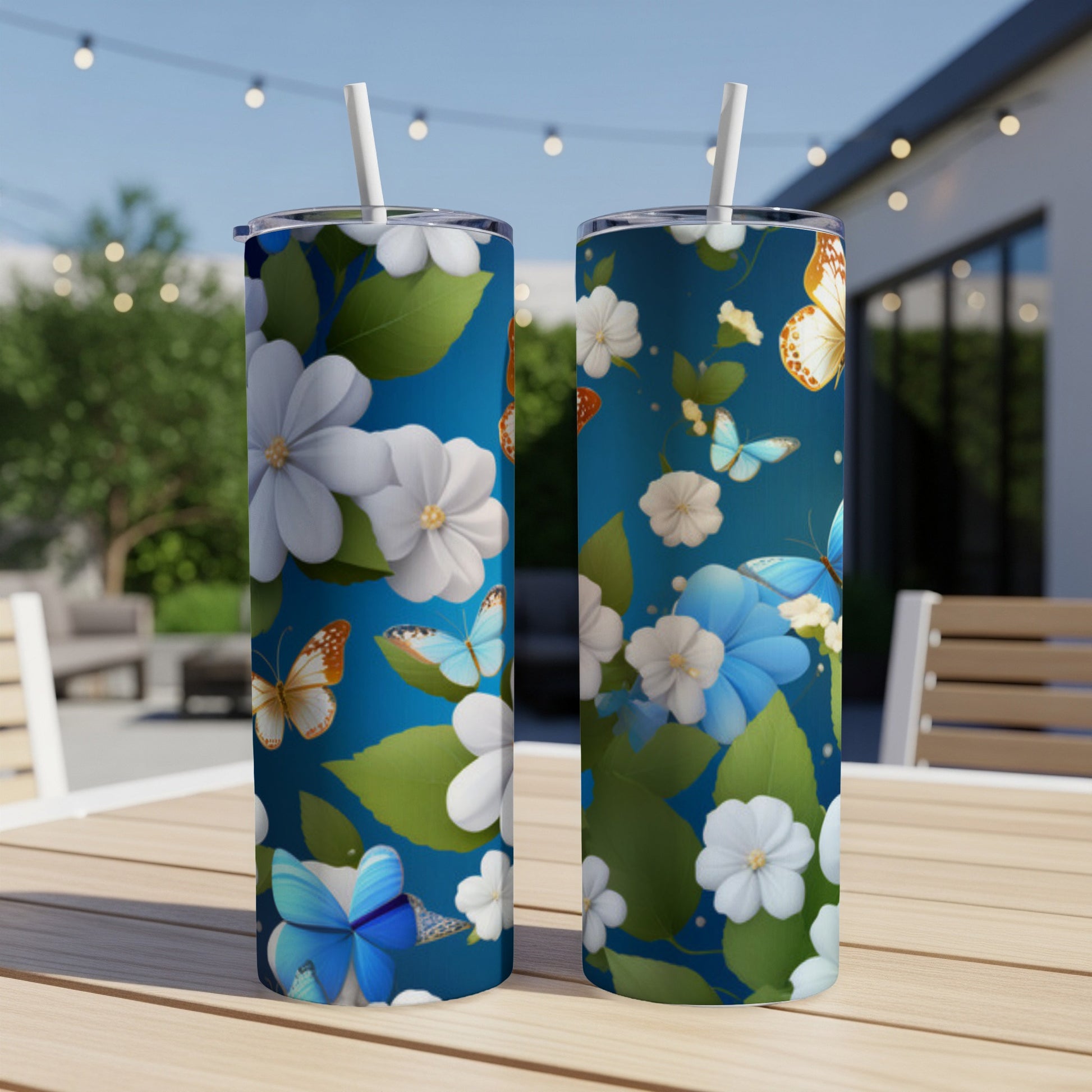 Two tumblers with a blue floral and butterfly pattern on an outdoor table.
