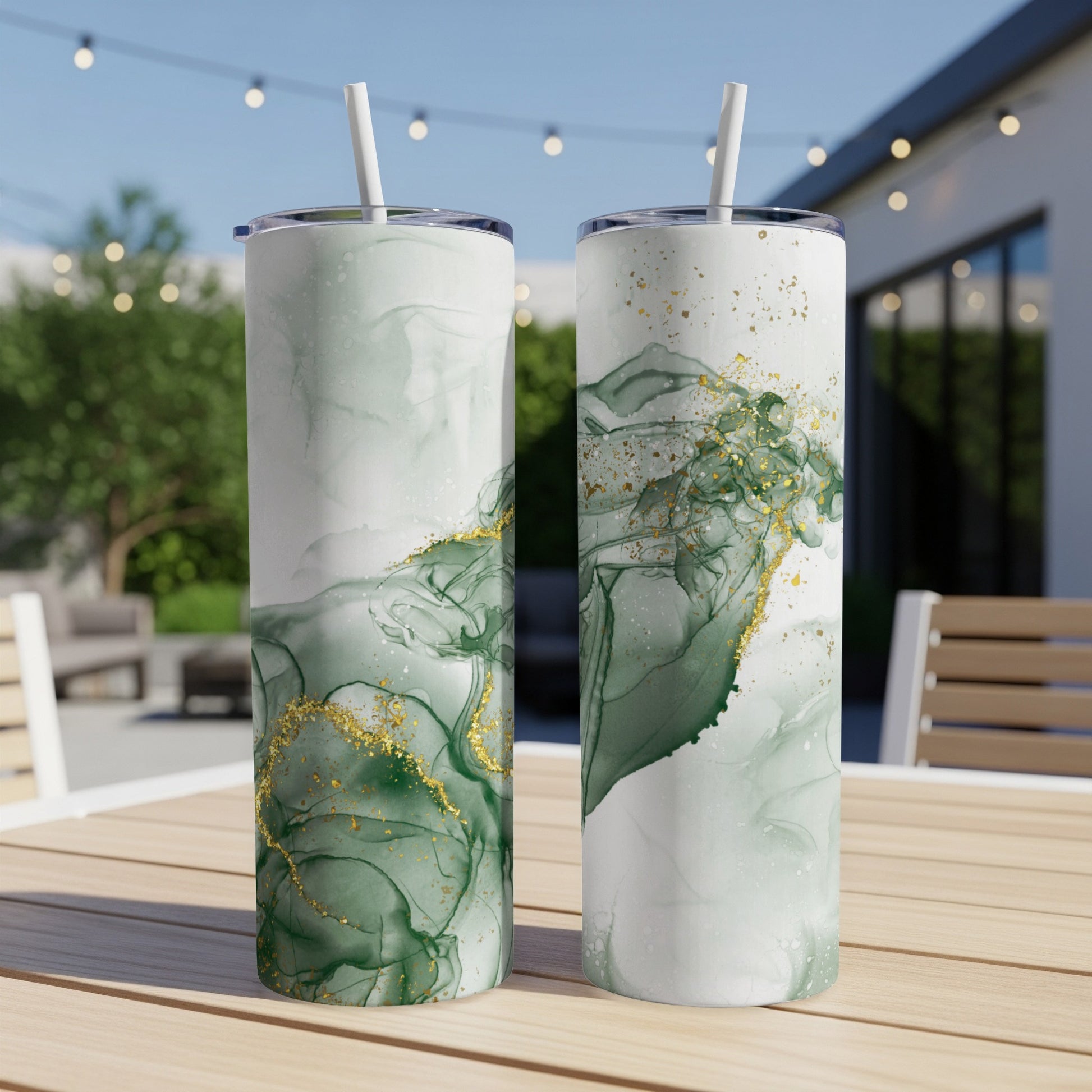 Two tall, slender tumblers with green and gold marbled design, on a wooden table.