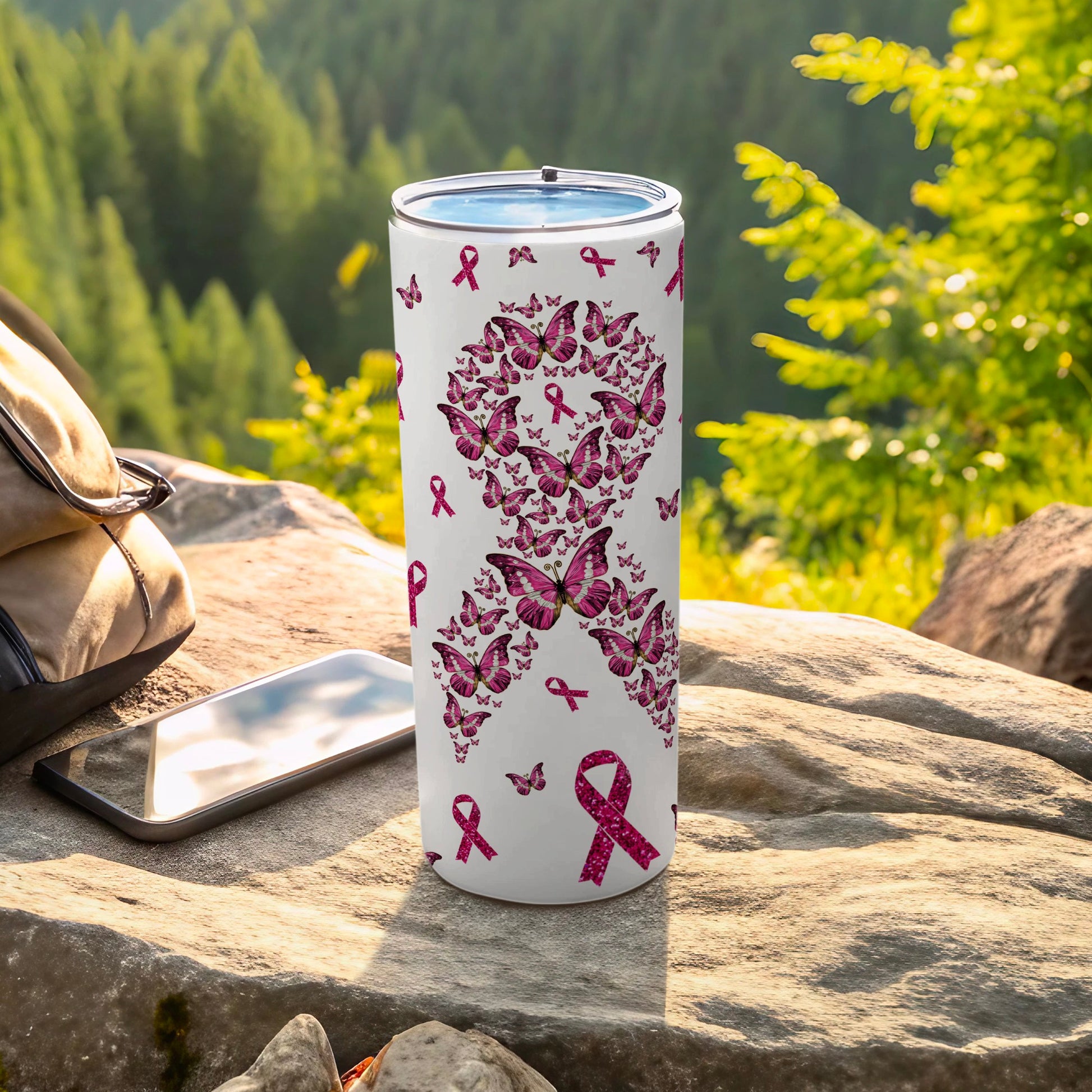 White tumbler with pink butterfly and ribbon pattern, outdoors.