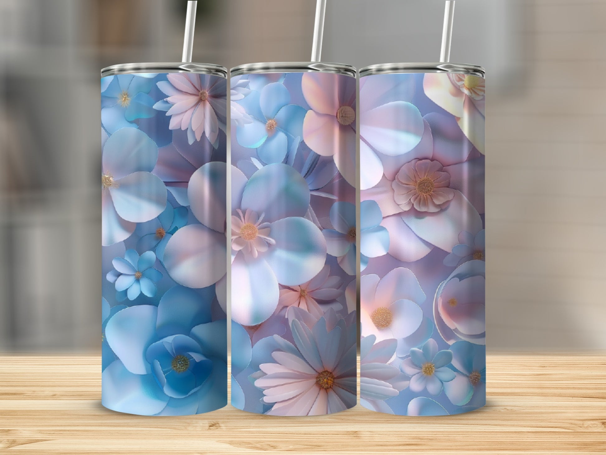 Three blue and pink floral tumblers with straws on a wooden surface.