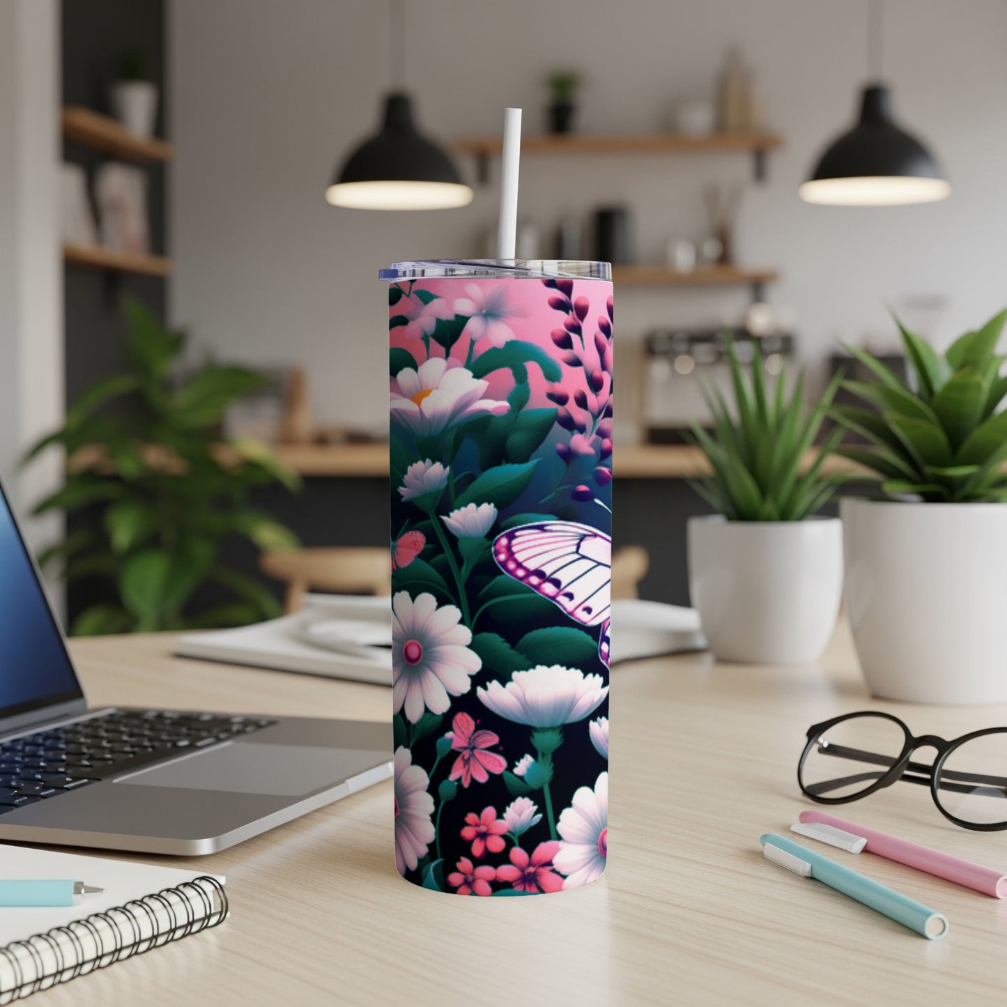 Pink floral tumbler with butterfly, on a desk with laptop and pens.