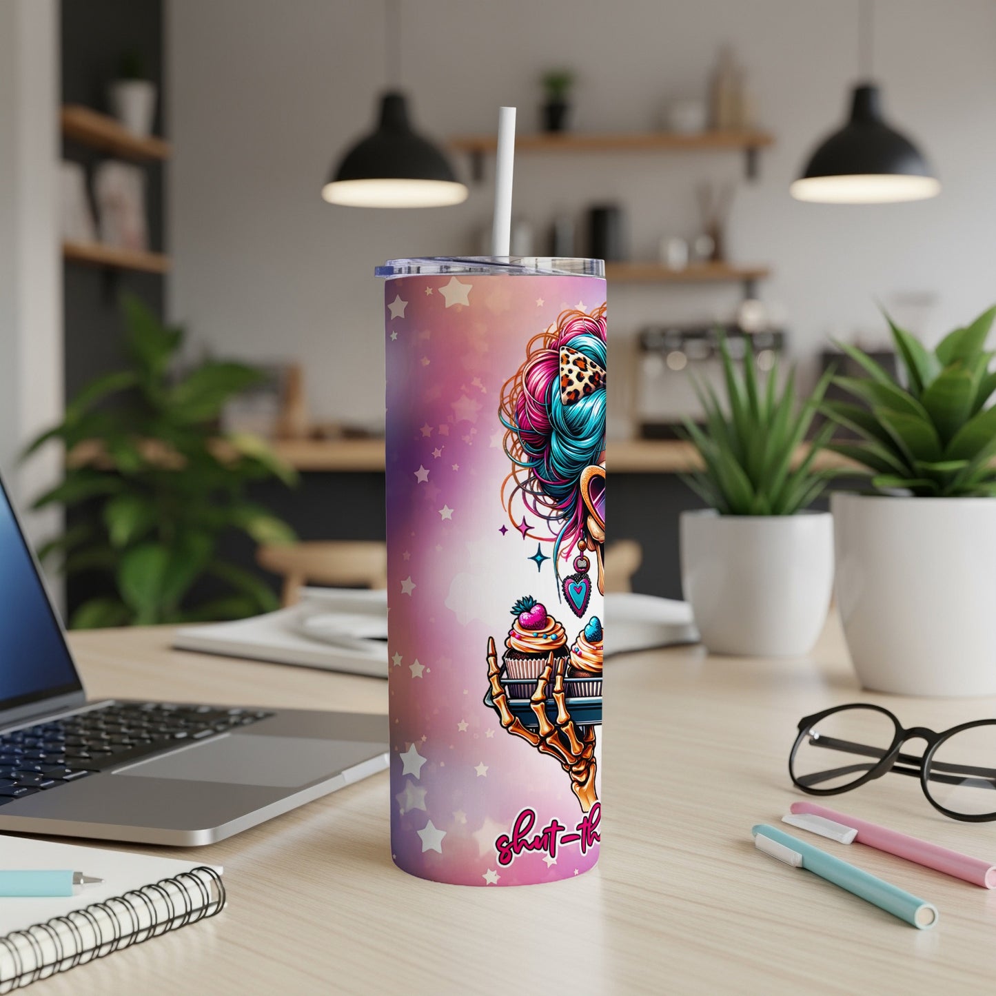 Tumbler with colorful cupcake art and skull graphic, on a desk.