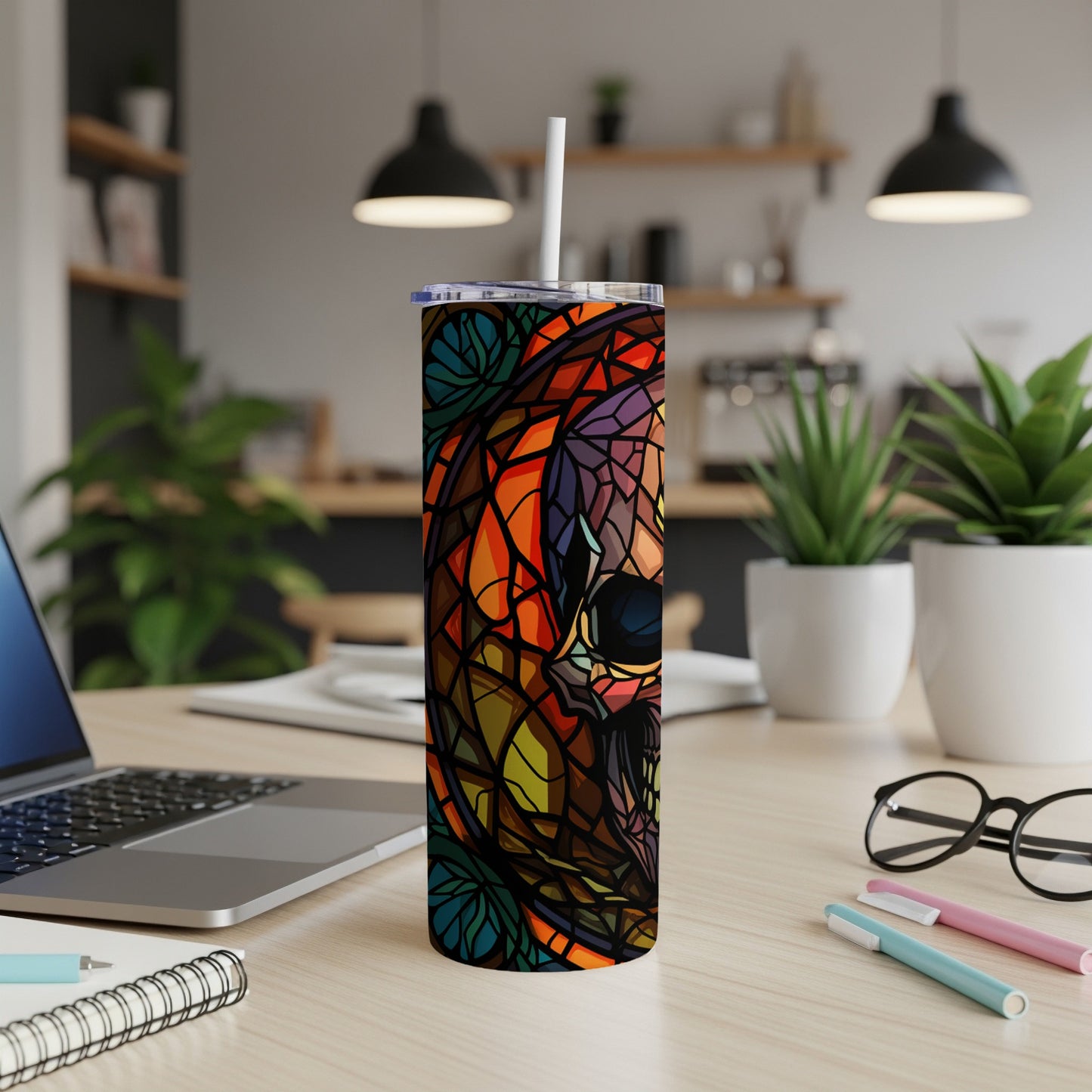 Stained glass skull tumbler with straw on desk.