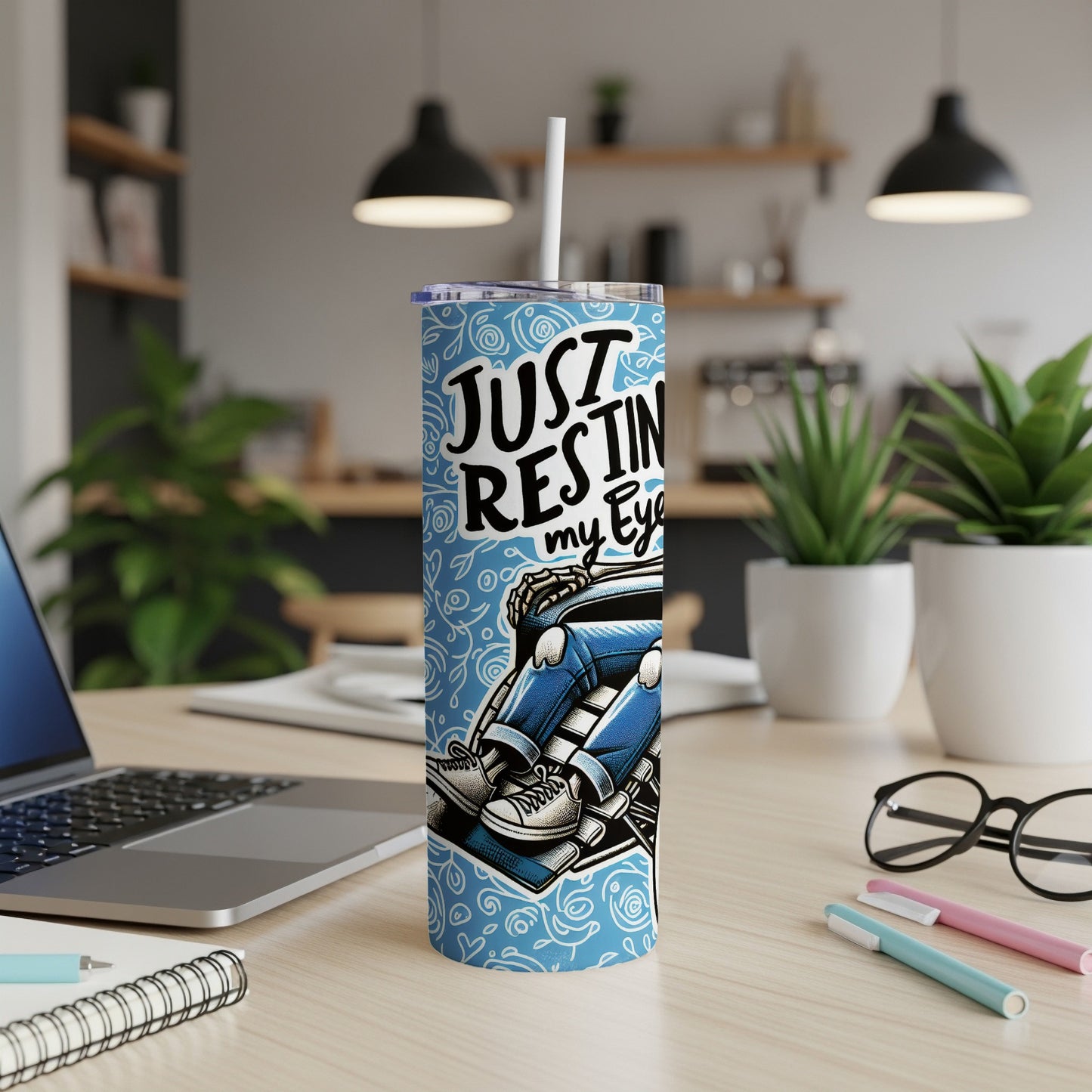 Blue tumbler with "Just Resting my Eyes" text and cartoon figure.