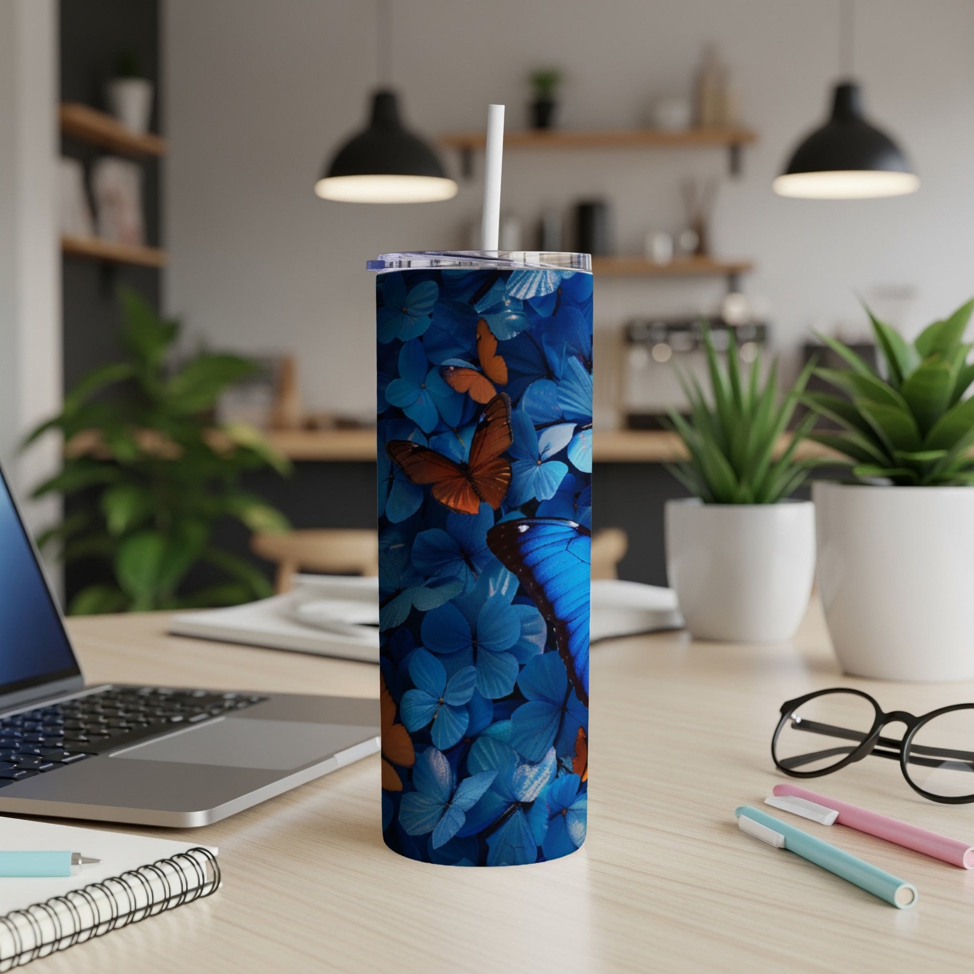 Blue tumbler with vibrant butterfly pattern, on a wooden desk.