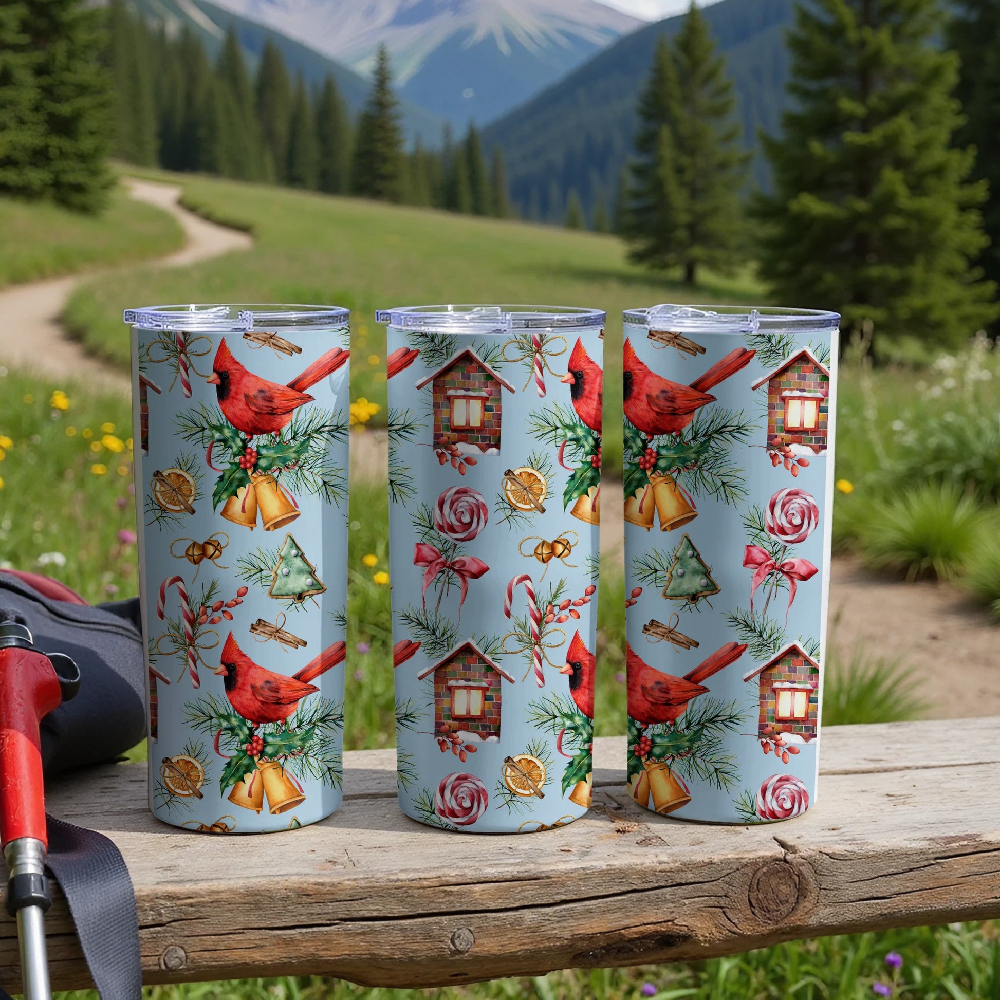 Three cardinal-themed tumblers with a Christmas pattern on a wooden surface.