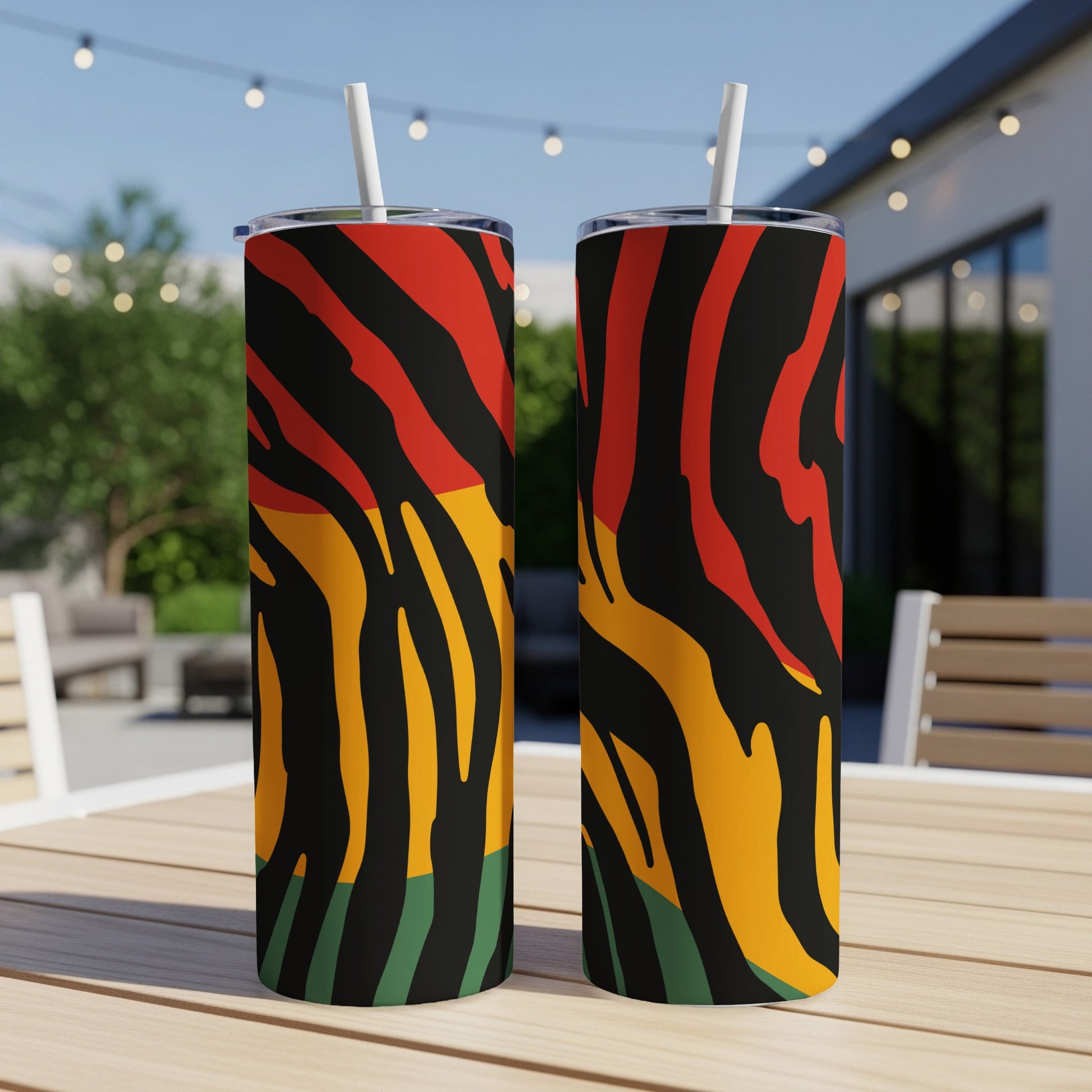 Two tumblers with red, yellow, green, and black stripe pattern sit on a wooden table.