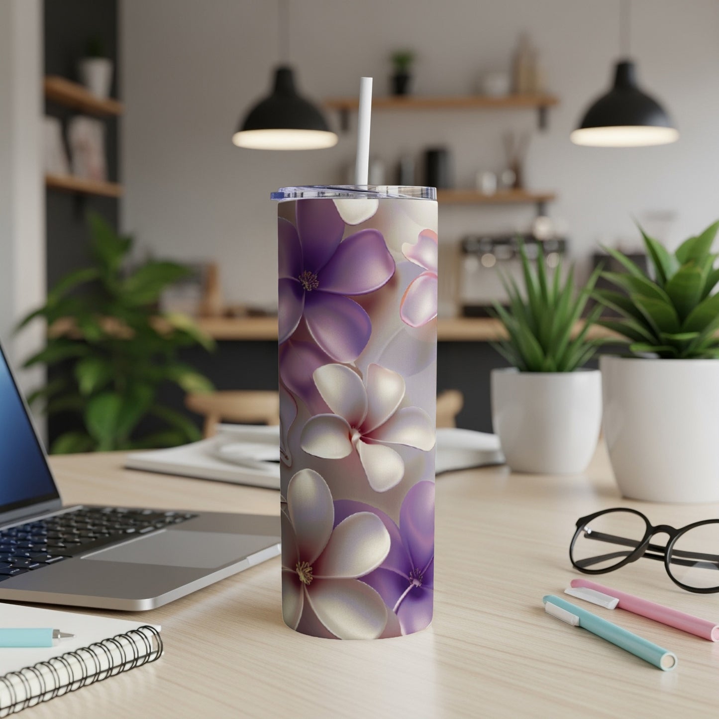Purple and white floral patterned tumbler with straw on a desk.