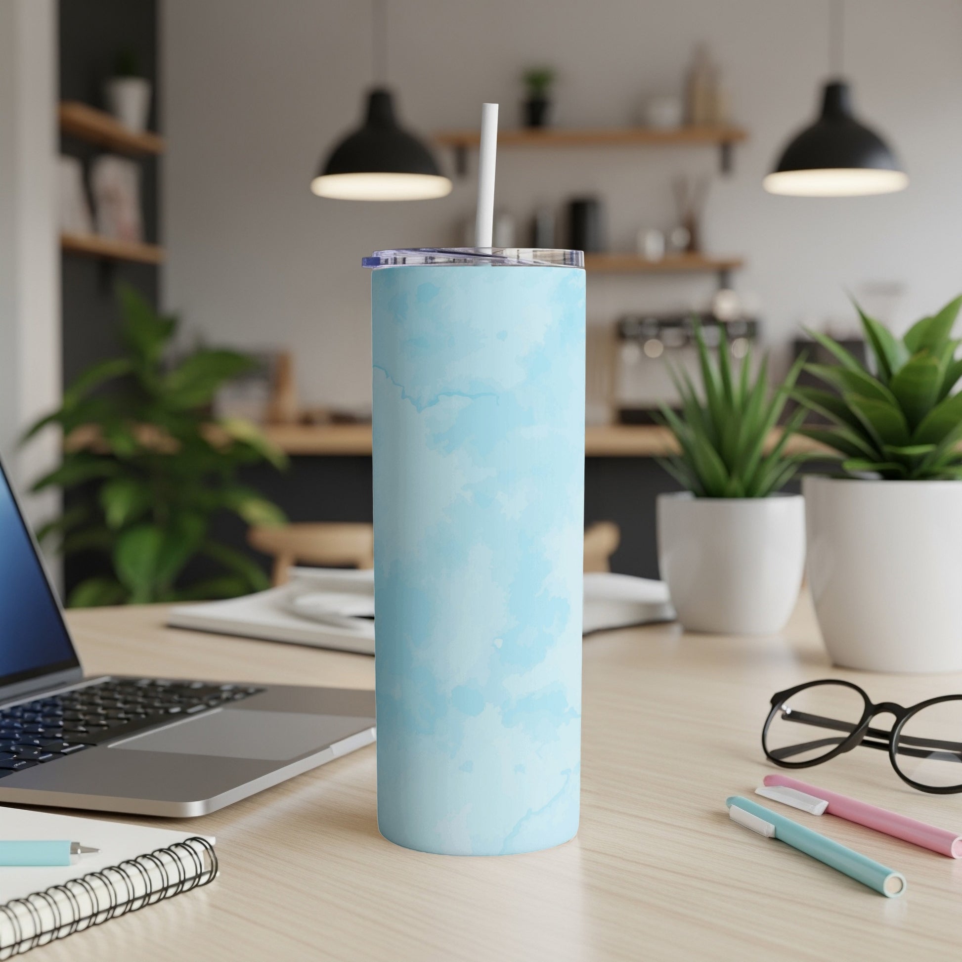 Light blue watercolor pattern tumbler with straw on a desk.