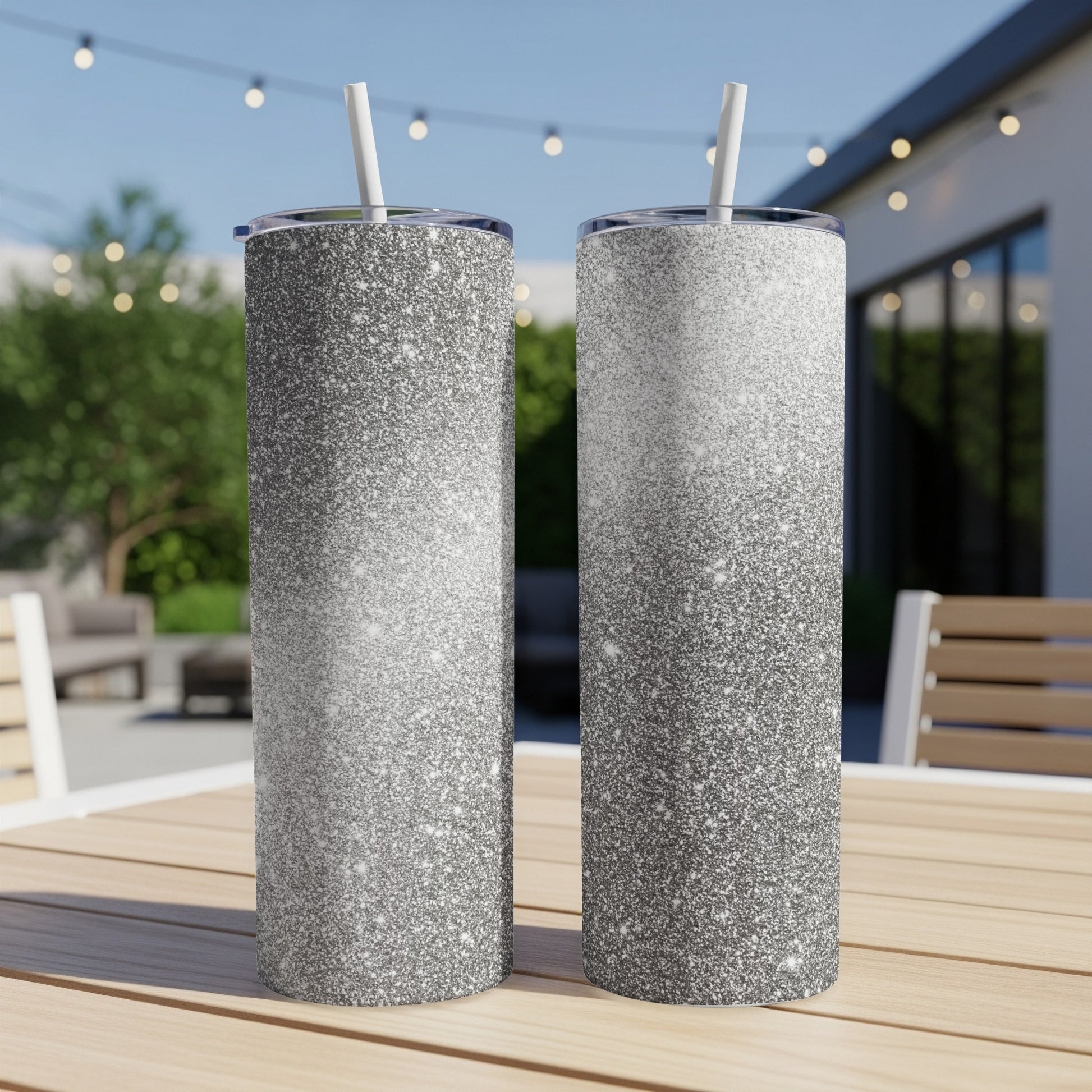 Two tall tumblers with a gradient silver glitter design and white straws.
