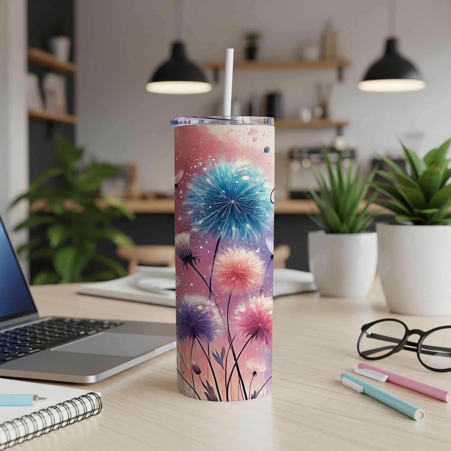 Tall tumbler with dandelion floral design and white straw on a desk.