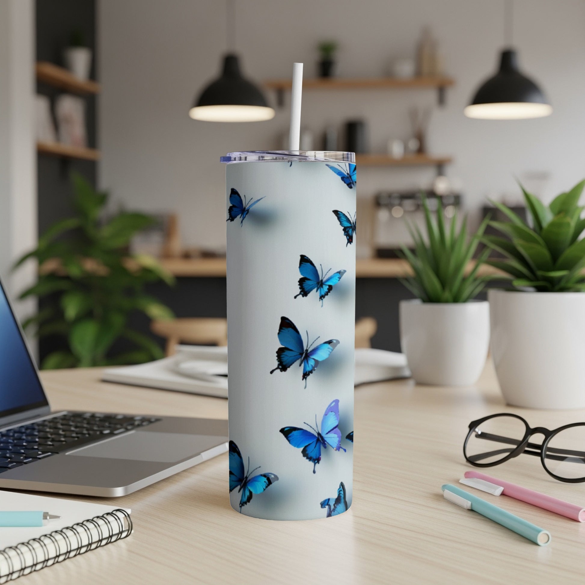 White tumbler with blue butterflies, straw, and desk items.