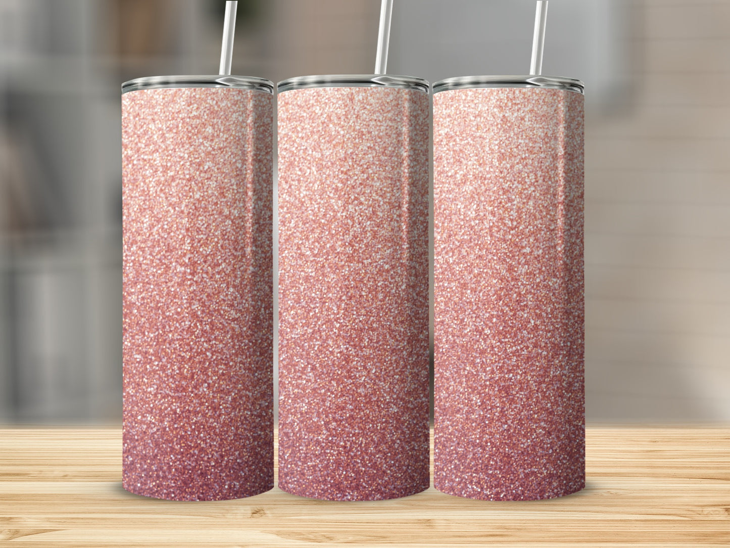 Three rose gold glitter tumblers with straws on a wooden surface.