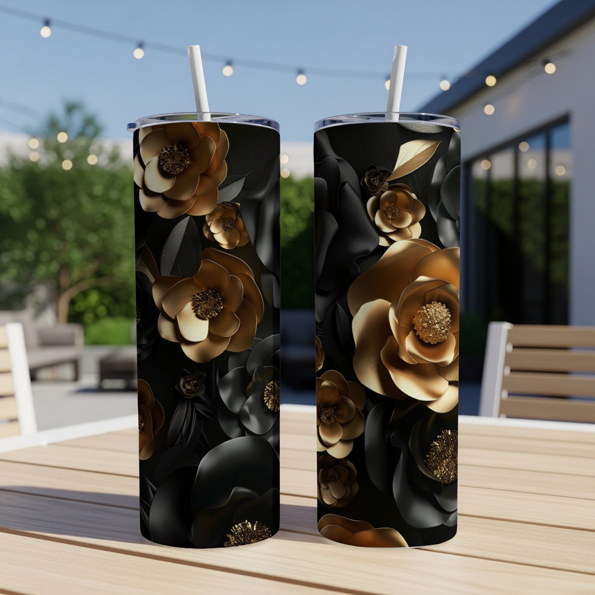 Two black tumblers with gold and black floral designs on a wooden table.