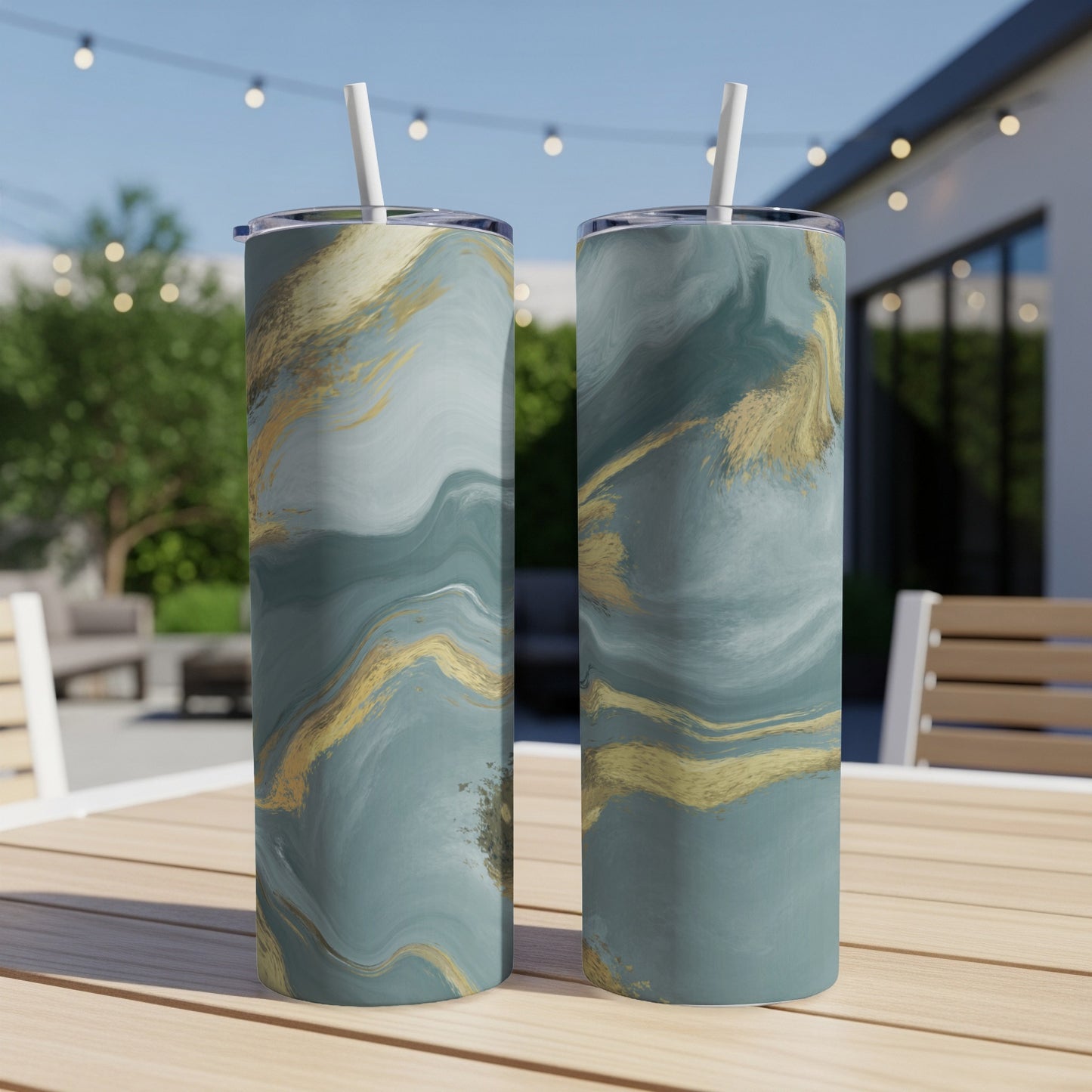 Two teal and gold marble pattern tumblers with straws on a wooden table.