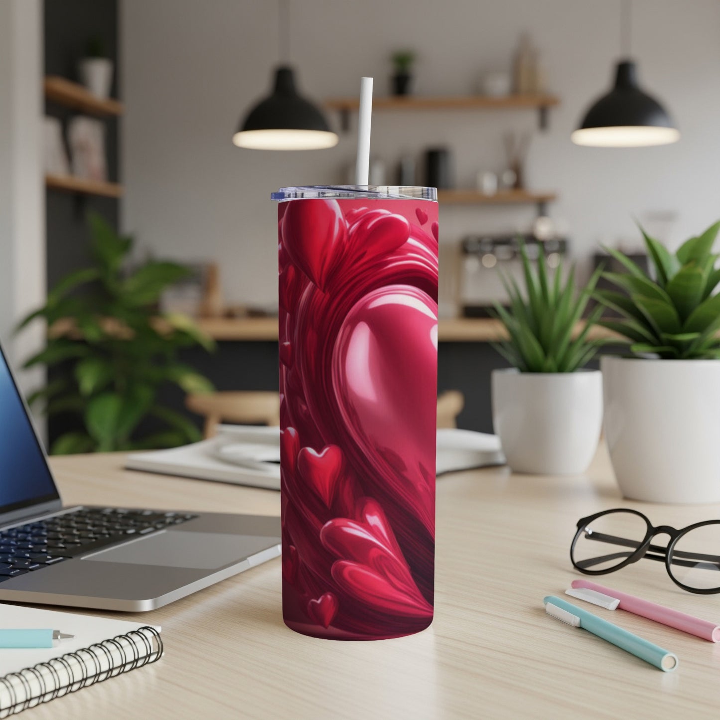 Red heart pattern on a tall tumbler with a straw, on a desk.