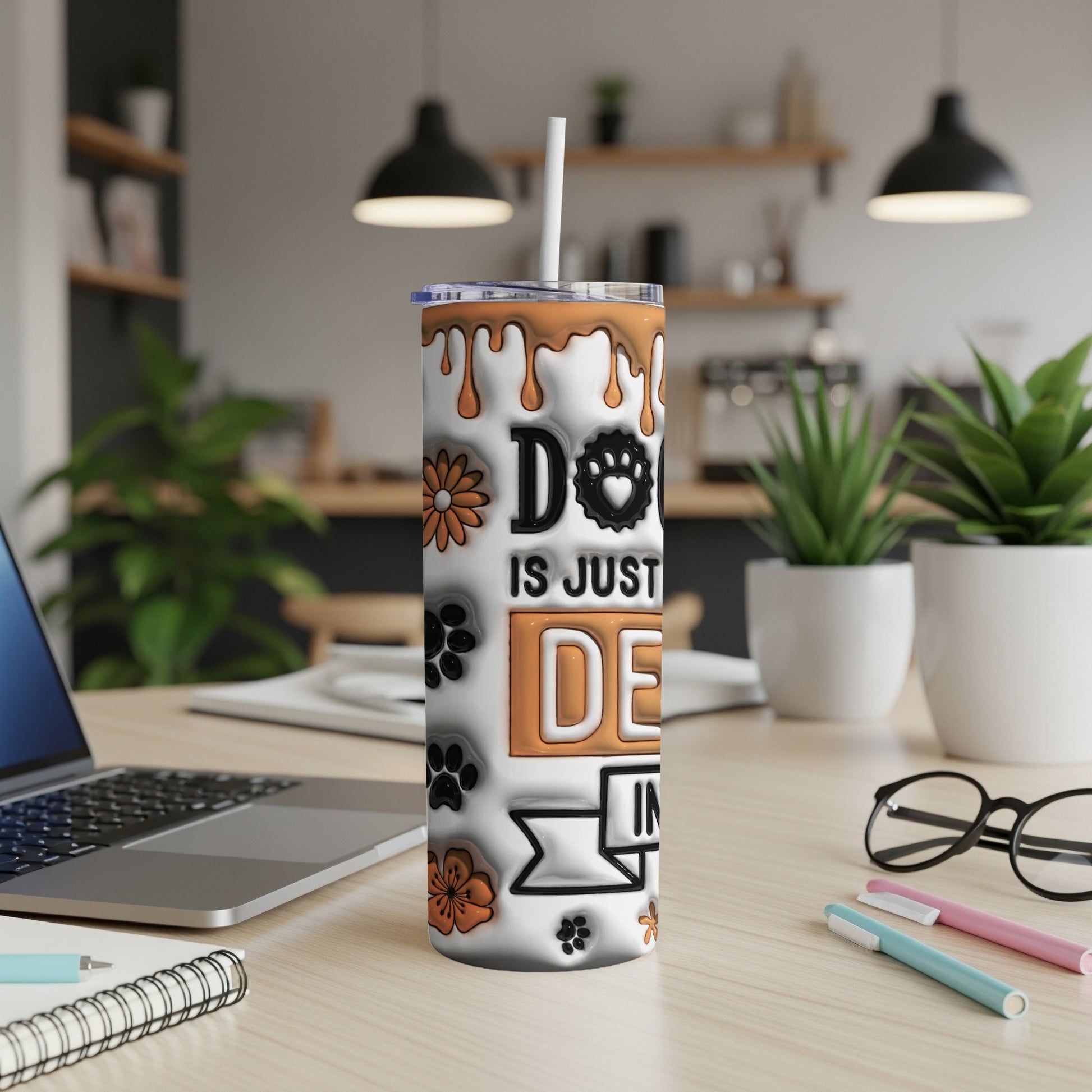 White tumbler with orange drip design and dog-themed graphics on a desk.