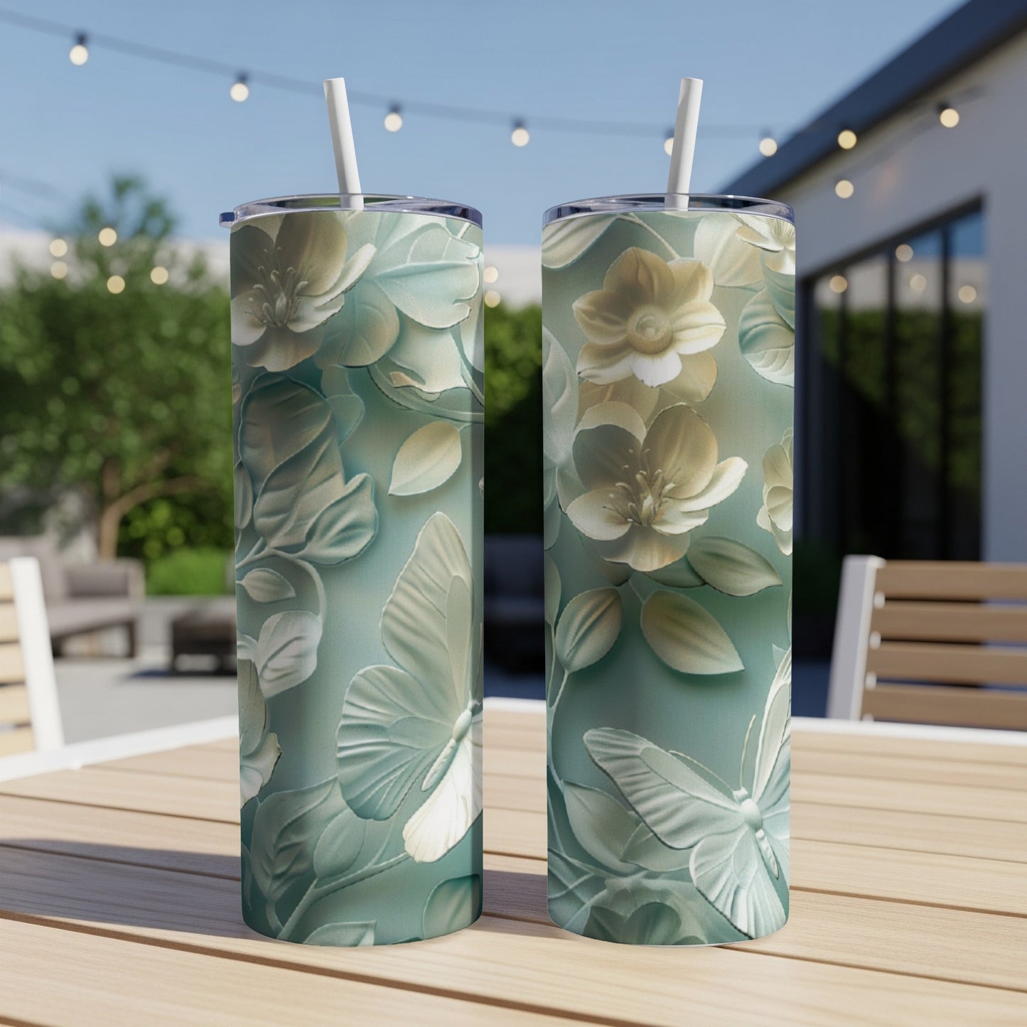 Two tumblers with raised floral and butterfly designs on a table.