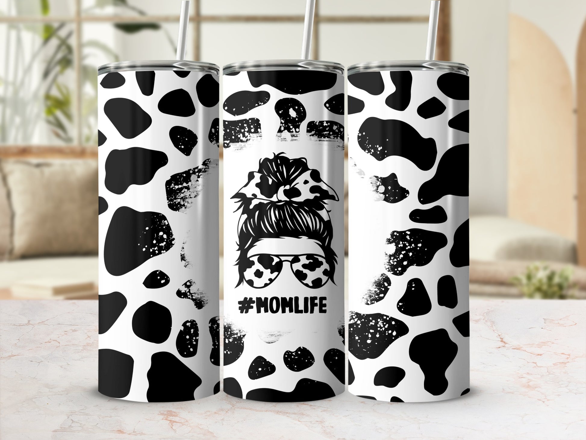 Black and white cow print tumbler with #MOMLIFE design.