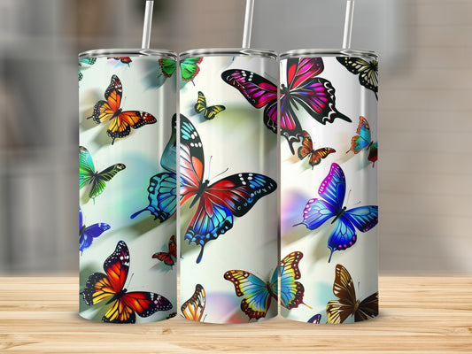 Three tumblers with colorful butterfly designs stand on a wooden surface.