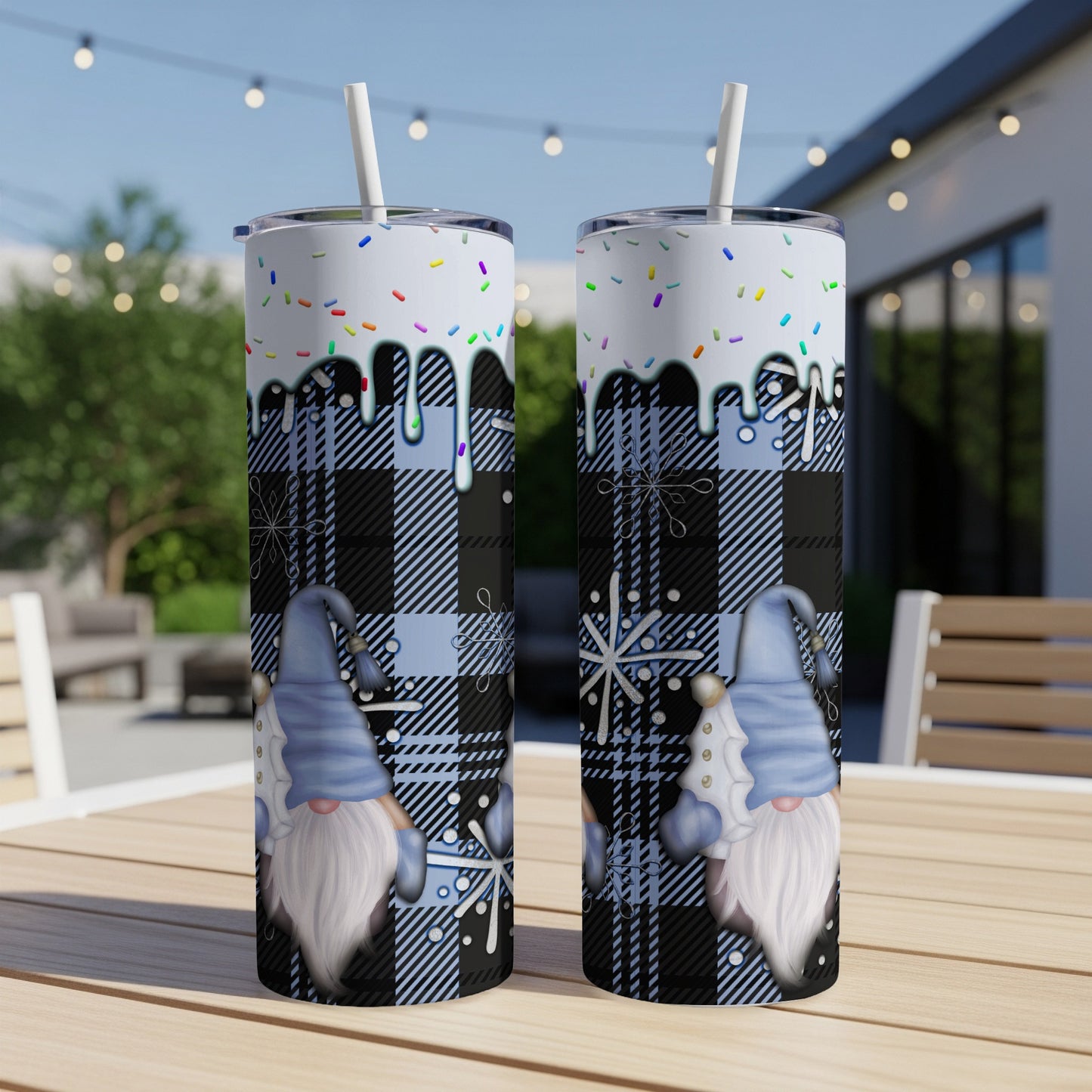 Two tumblers with blue plaid, snowflakes, and gnomes on a patio table.