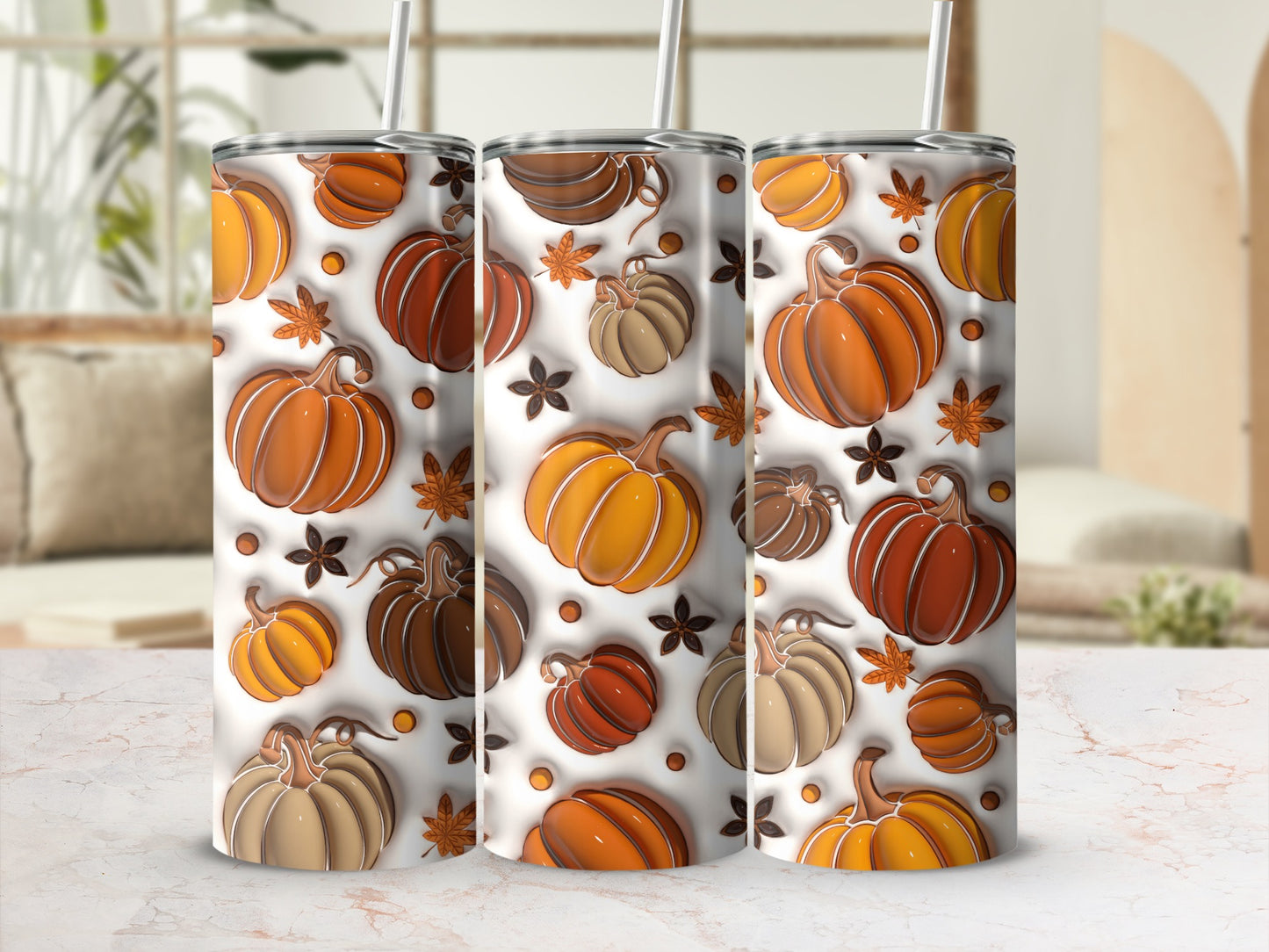 Three tumblers with a pumpkin and leaf pattern on a marbled surface.