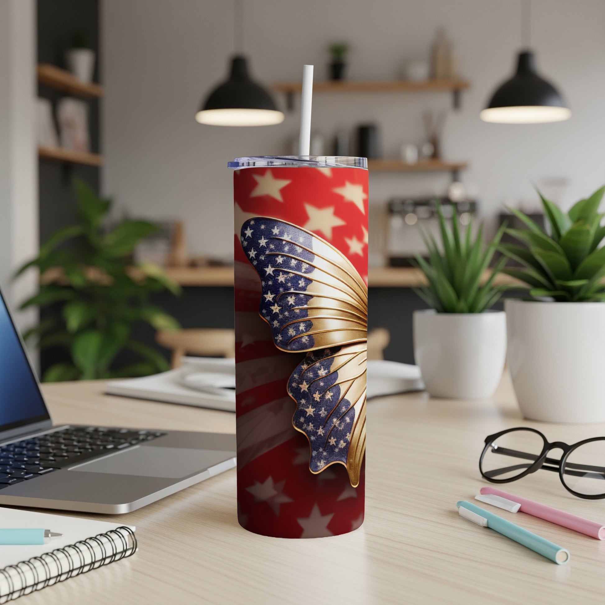 Red and gold patriotic butterfly tumbler with straw on a desk.