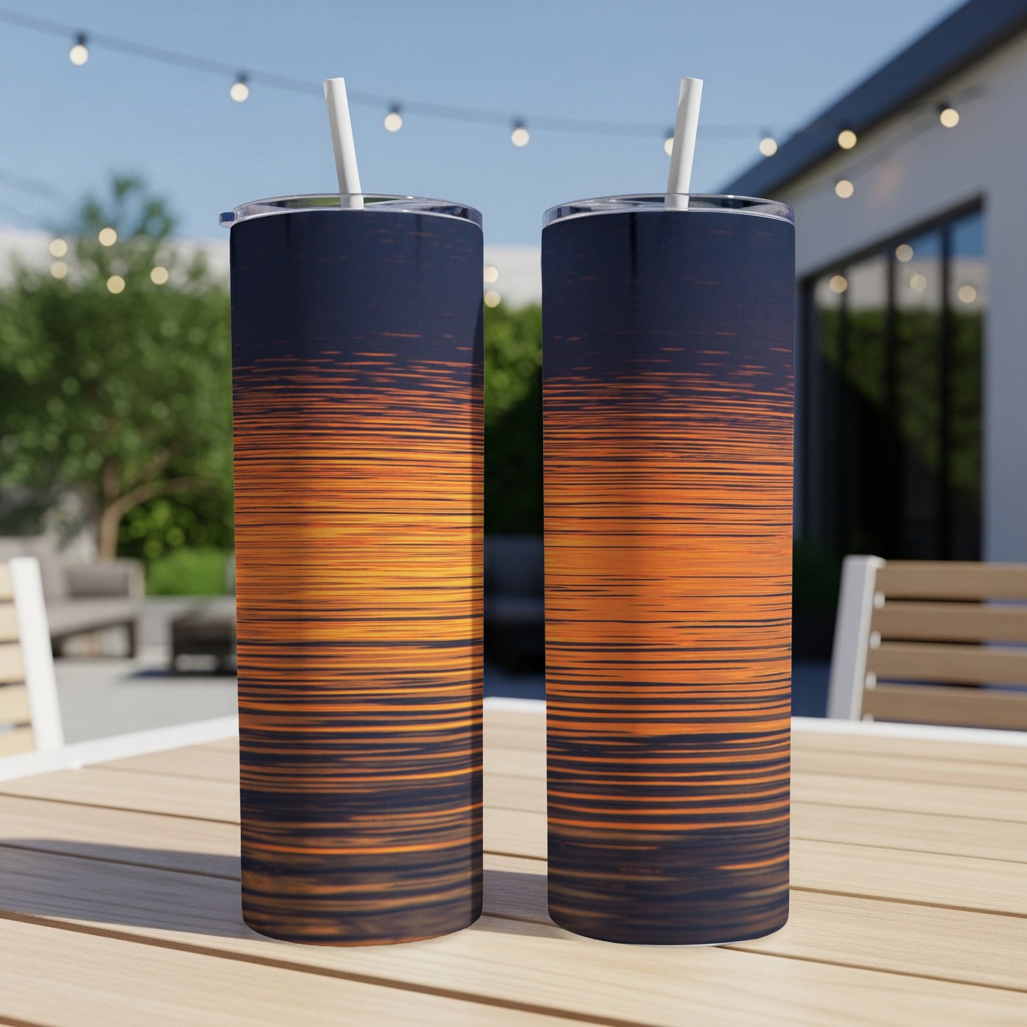 Two skinny tumblers with a sunset stripe pattern sit on a table.