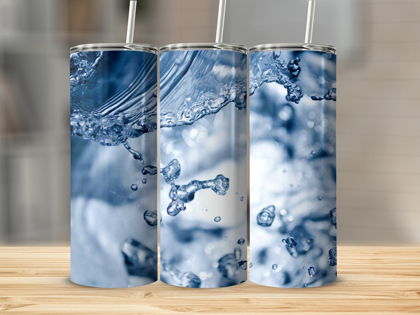 Three tumblers with abstract water splash graphics on a wooden surface.