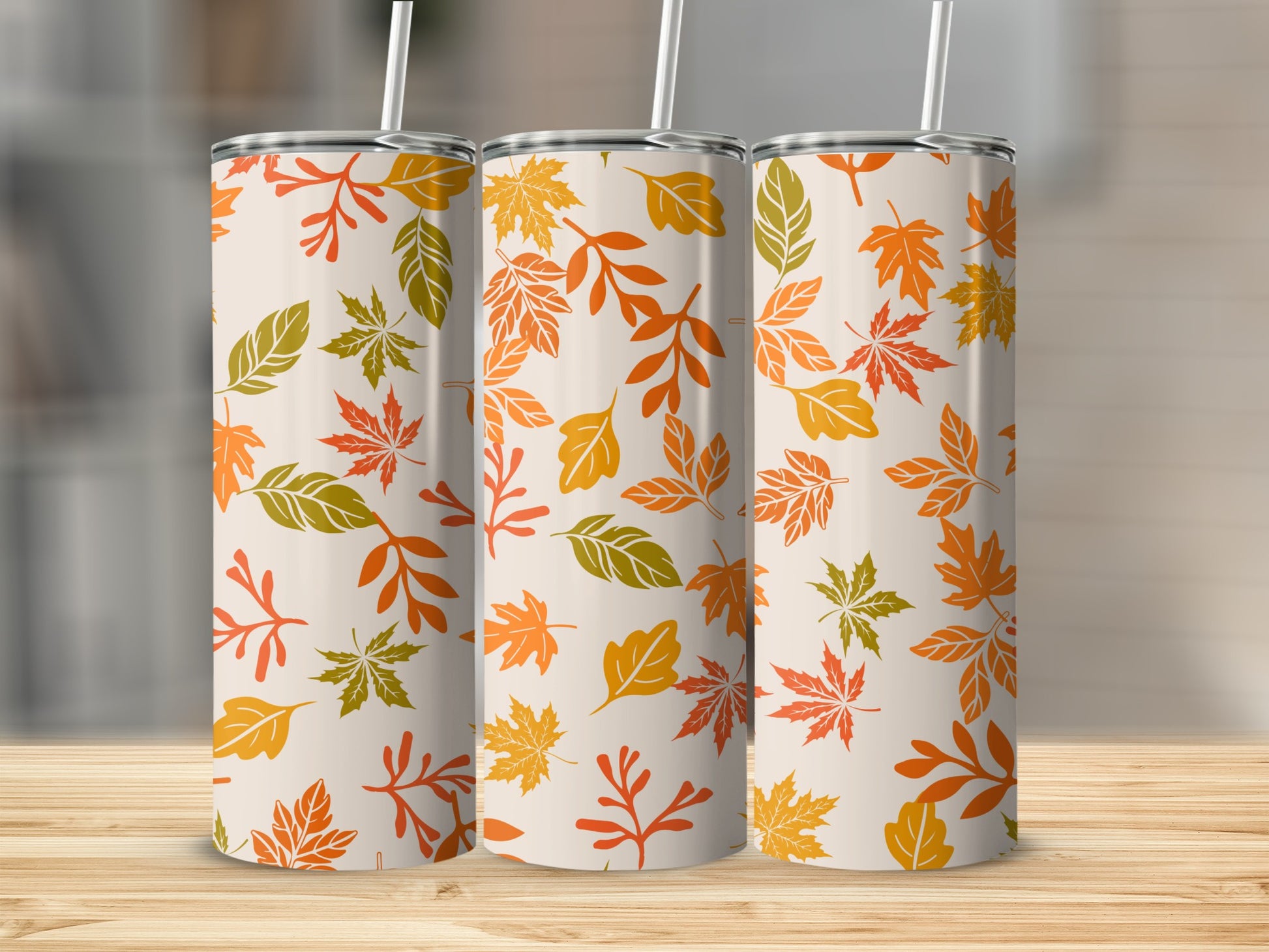 Three tumblers with a repeating pattern of autumn leaves in orange, green, and yellow.