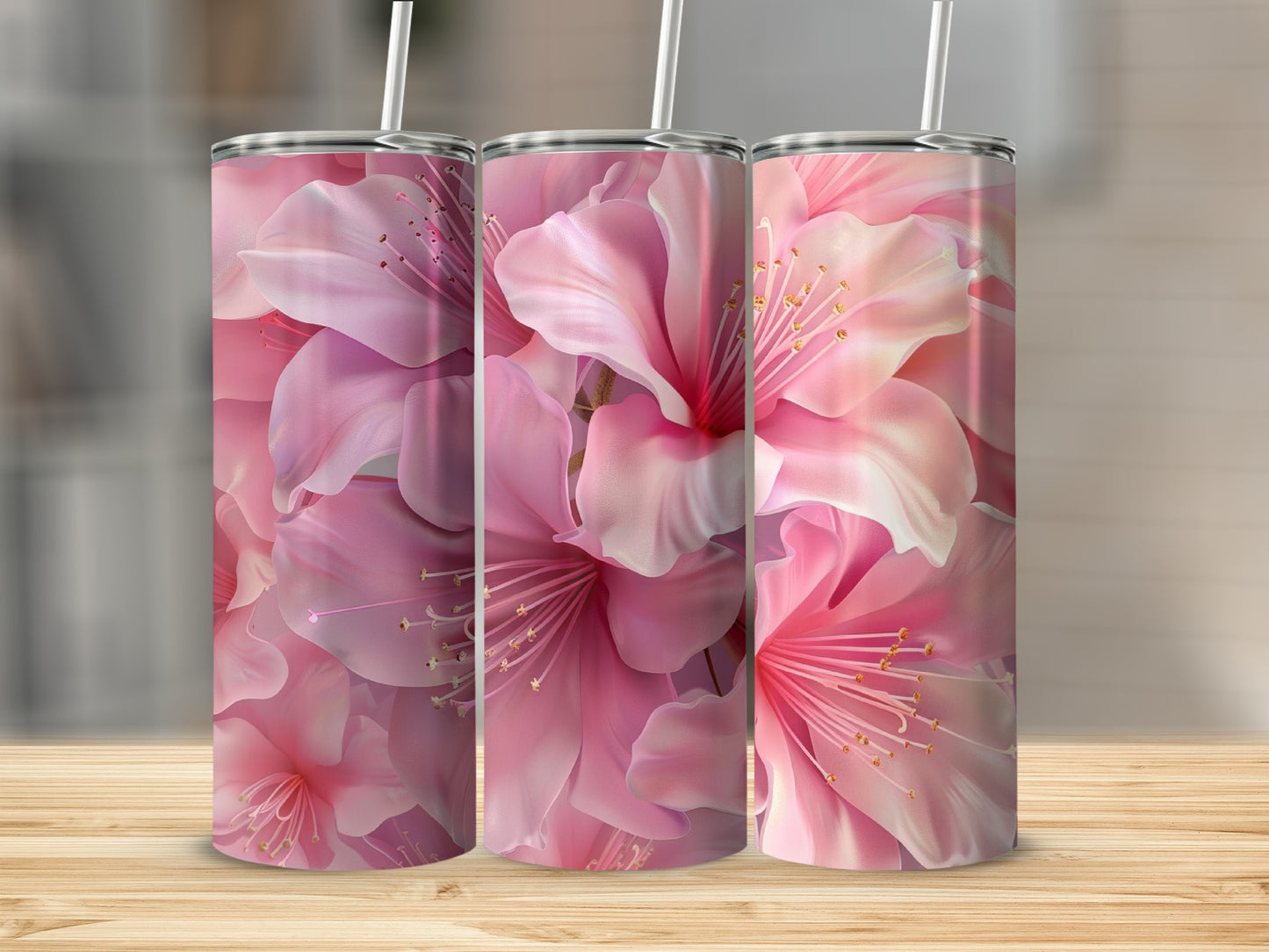 Three pink floral tumblers with straws on a wooden surface.
