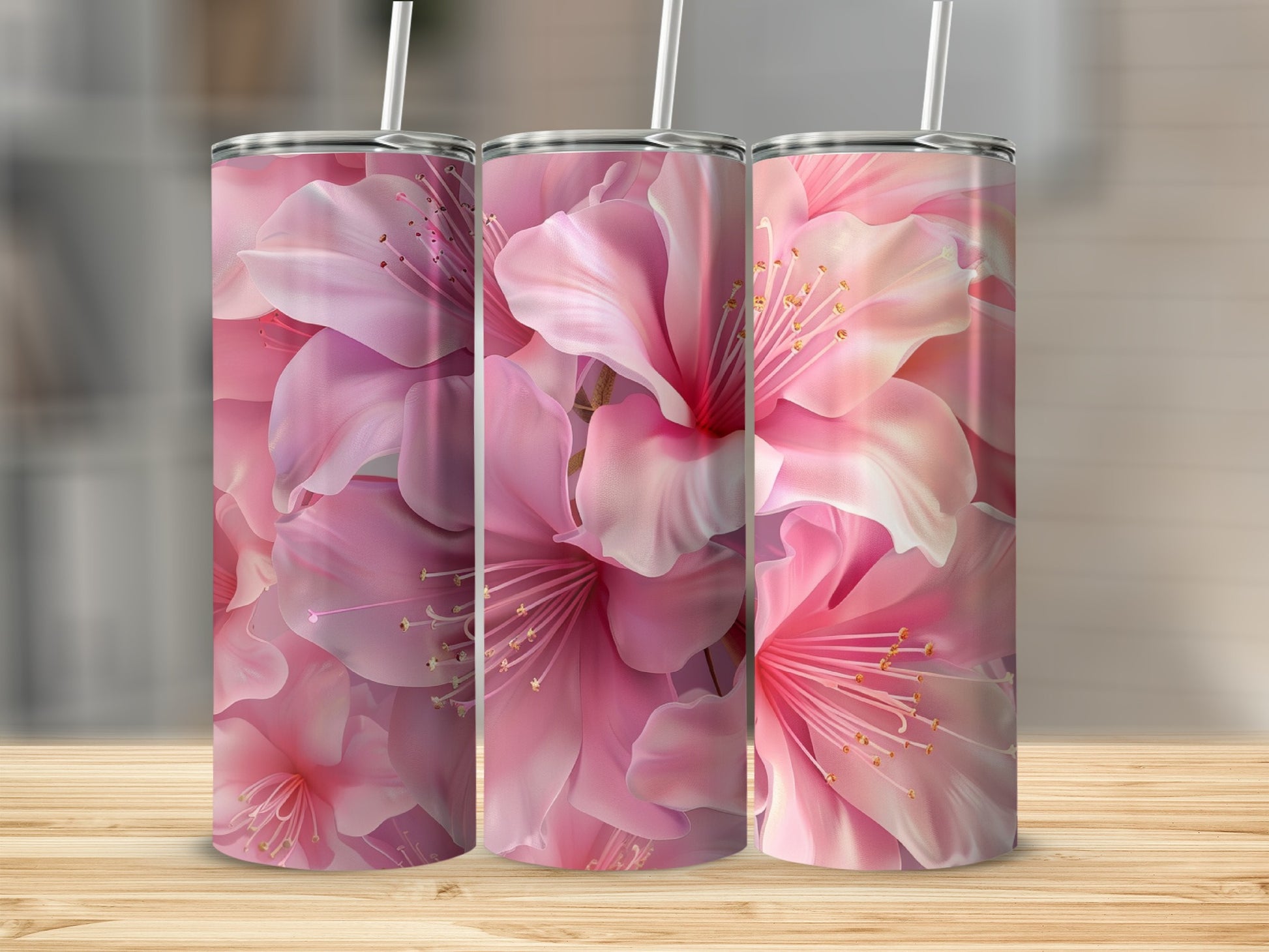 Three pink floral tumblers with straws on a wooden surface.