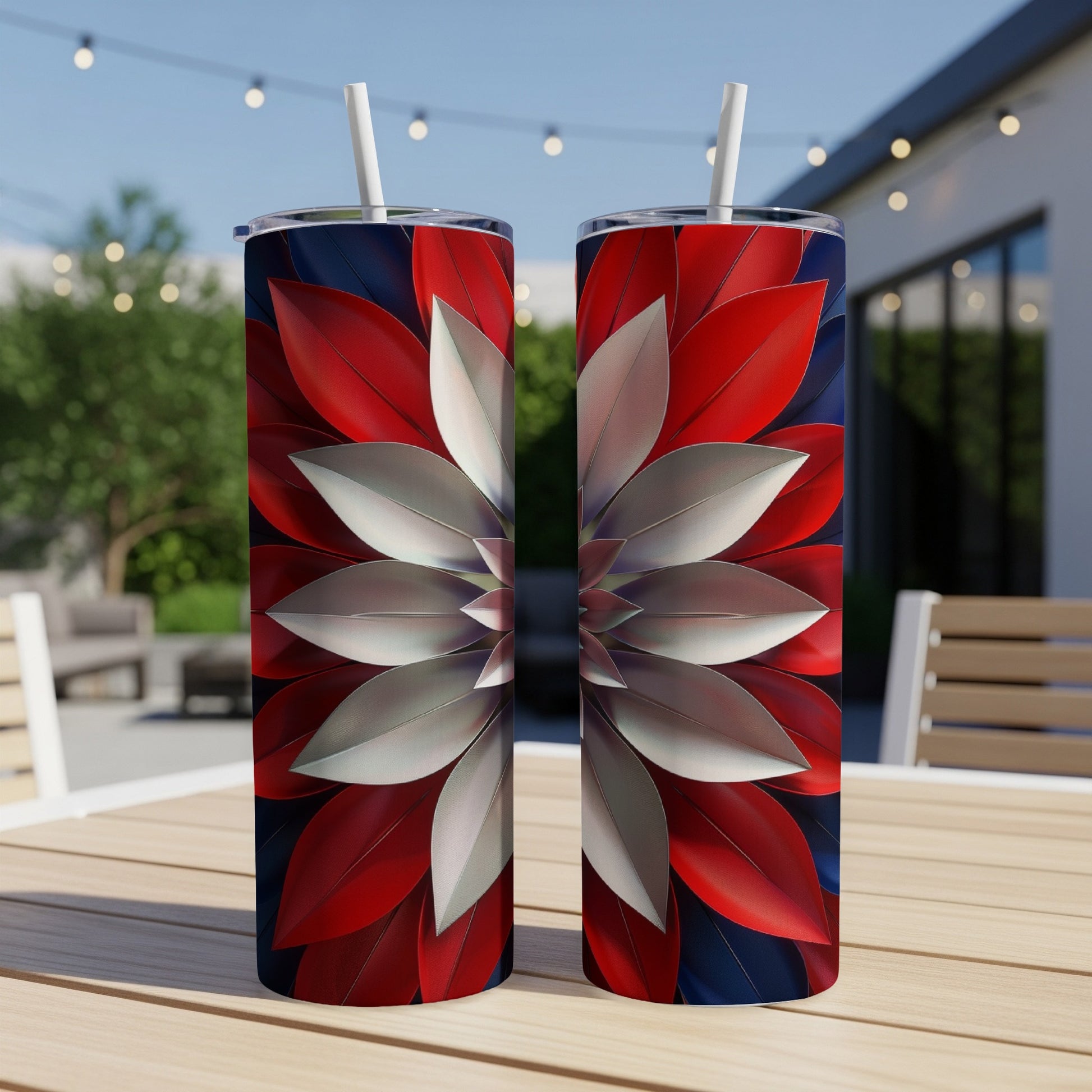 Two red, white, and blue floral pattern tumblers with straws on a table.