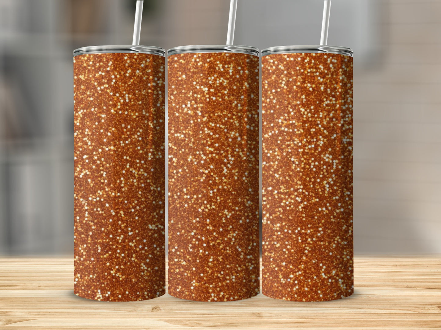 Three tall glitter tumblers with straws on a wooden surface.