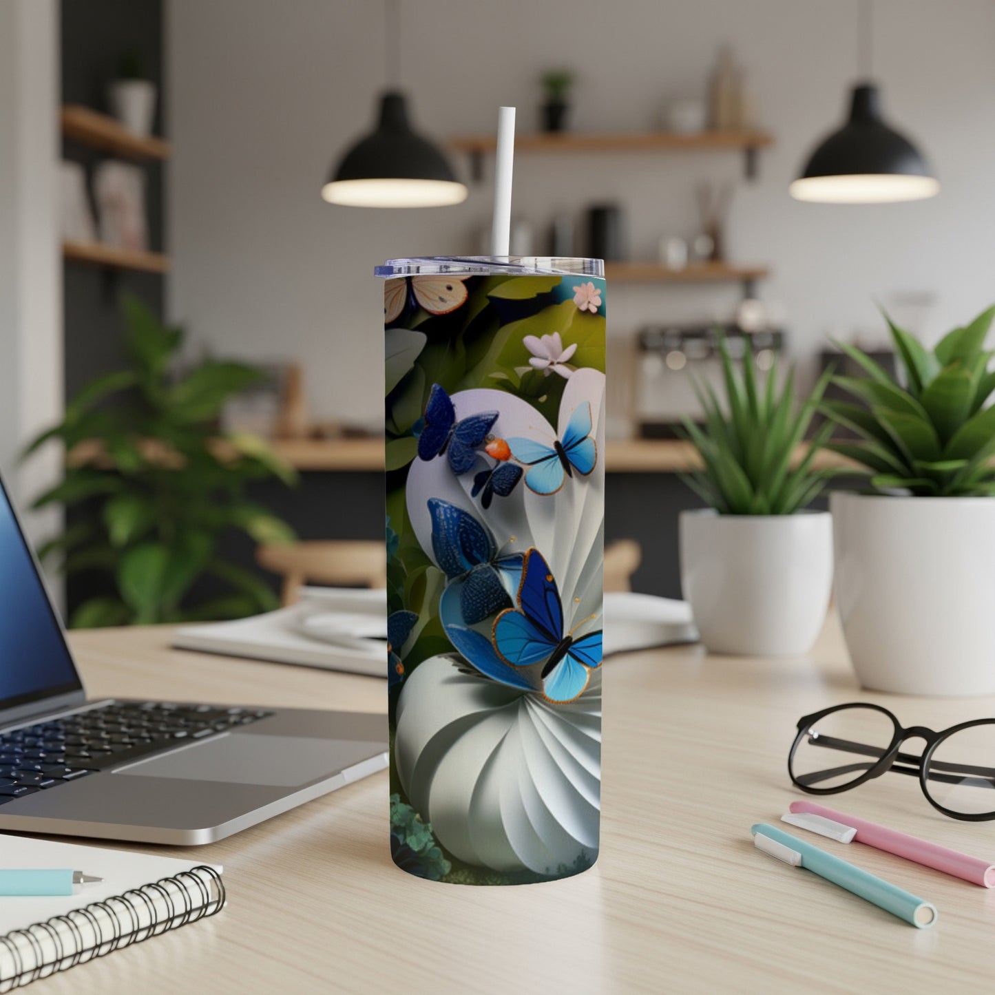 Tall tumbler with blue butterflies and white swirls on a desk.