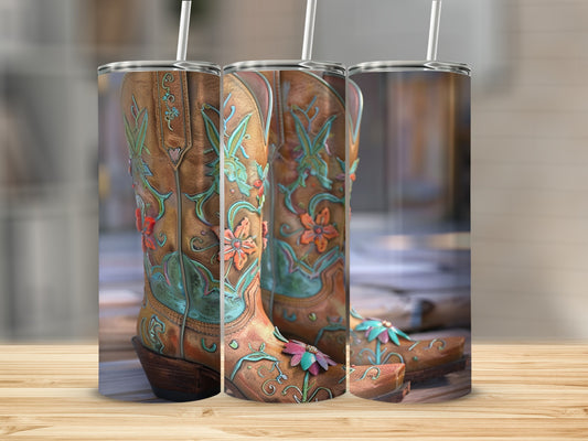 Three tan cowboy boots with floral embroidery displayed on a wooden surface.