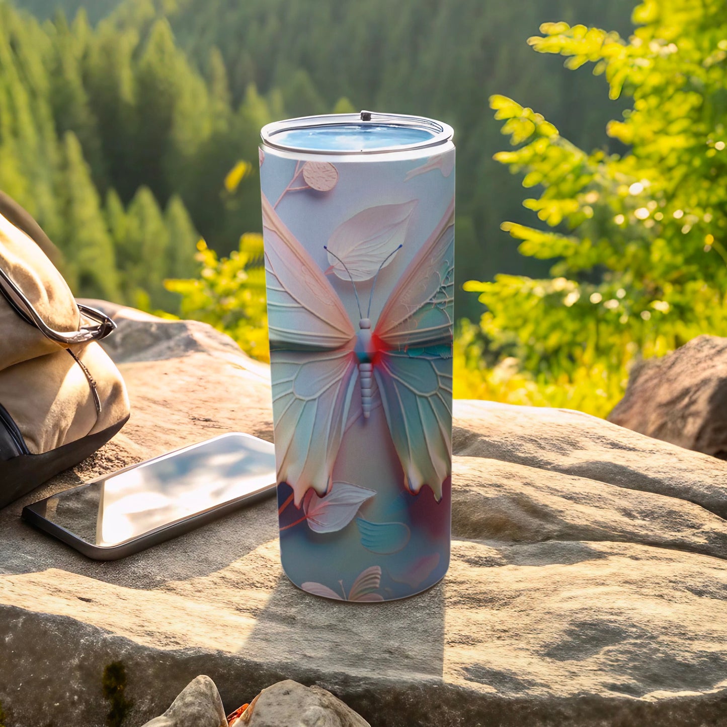 Tumbler with pale butterfly and floral pattern on rocks, outdoors.