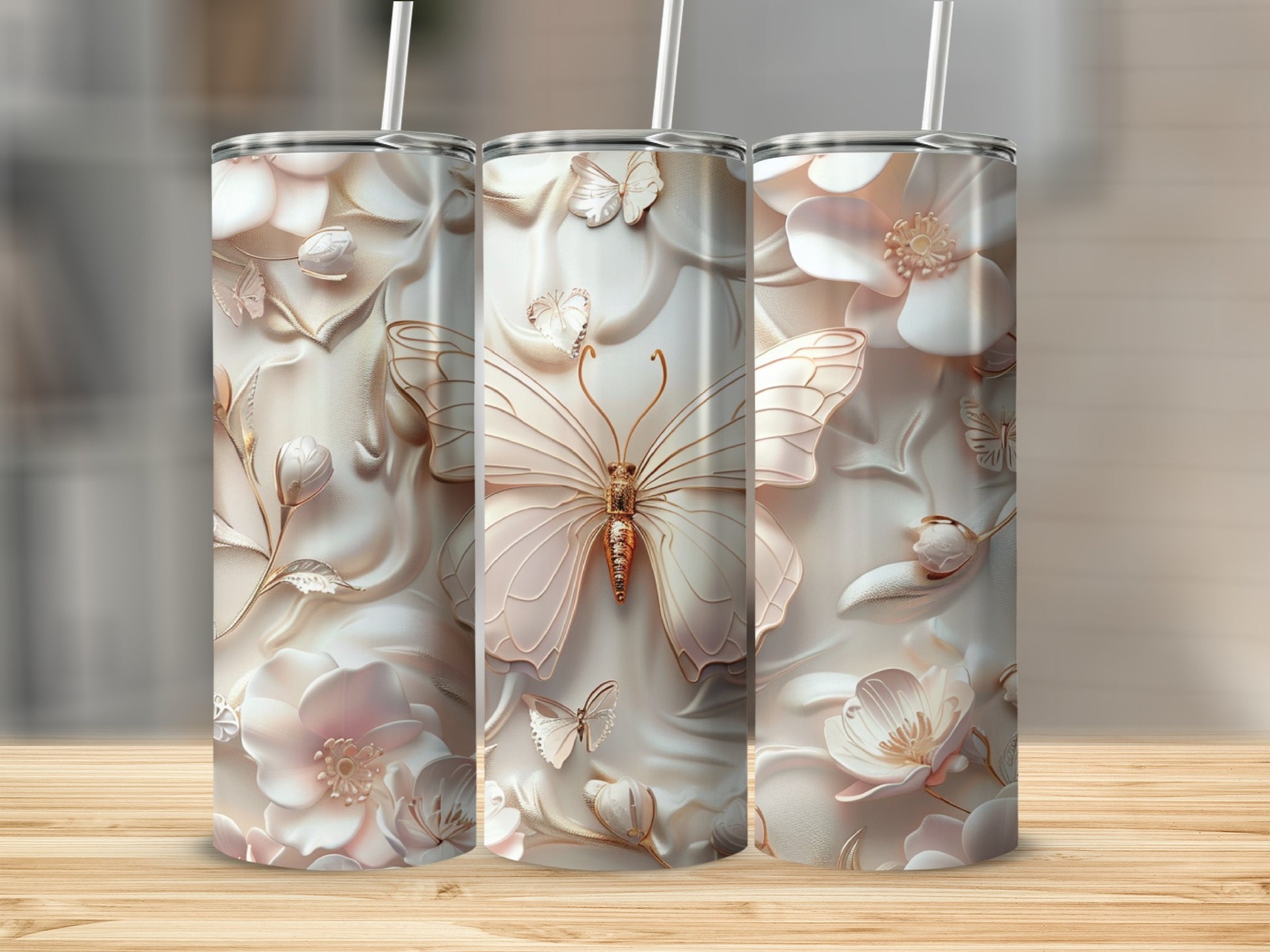 Three tall tumblers with embossed butterflies and flowers, on a wooden surface.