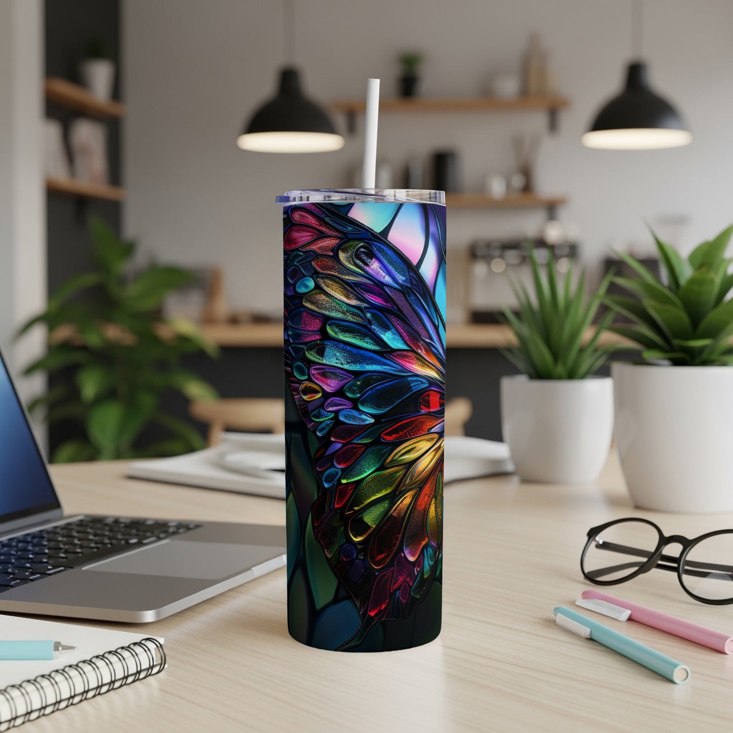 Colorful stained-glass butterfly tumbler with straw on a desk.