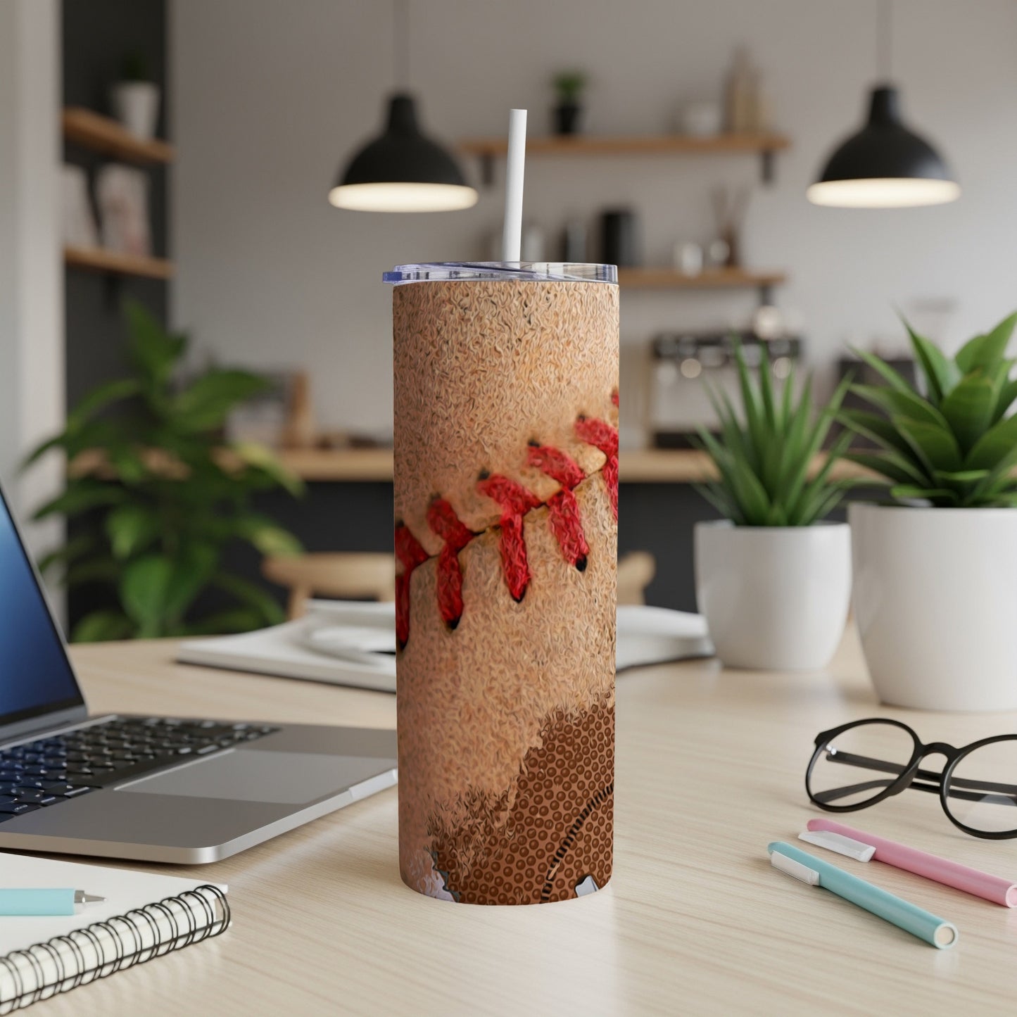Tumbler with baseball stitching and laces on a desk.