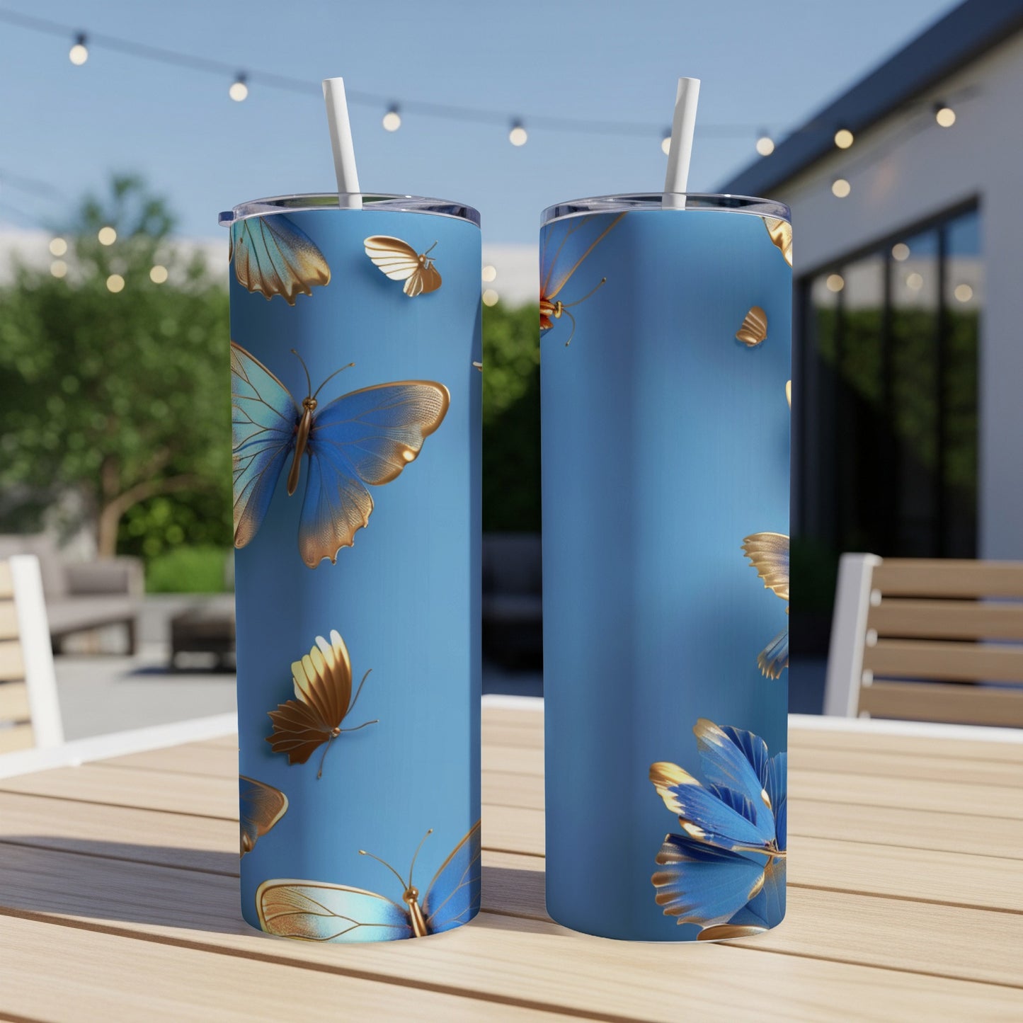 Two blue tumblers with golden butterflies against a blurred outdoor background.