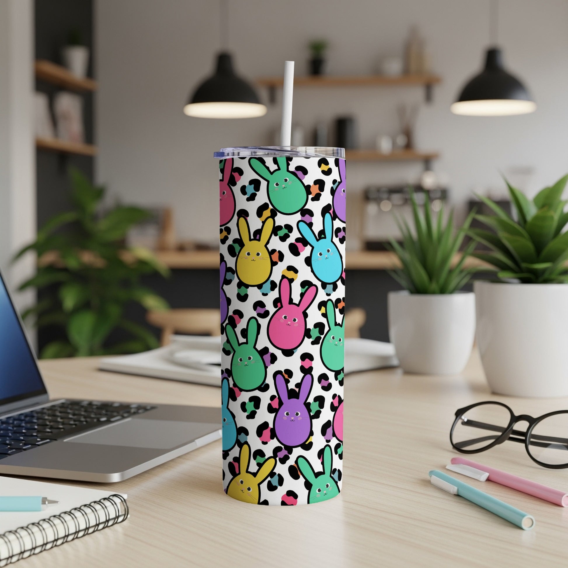 Colorful bunny pattern tumbler with straw on a desk.