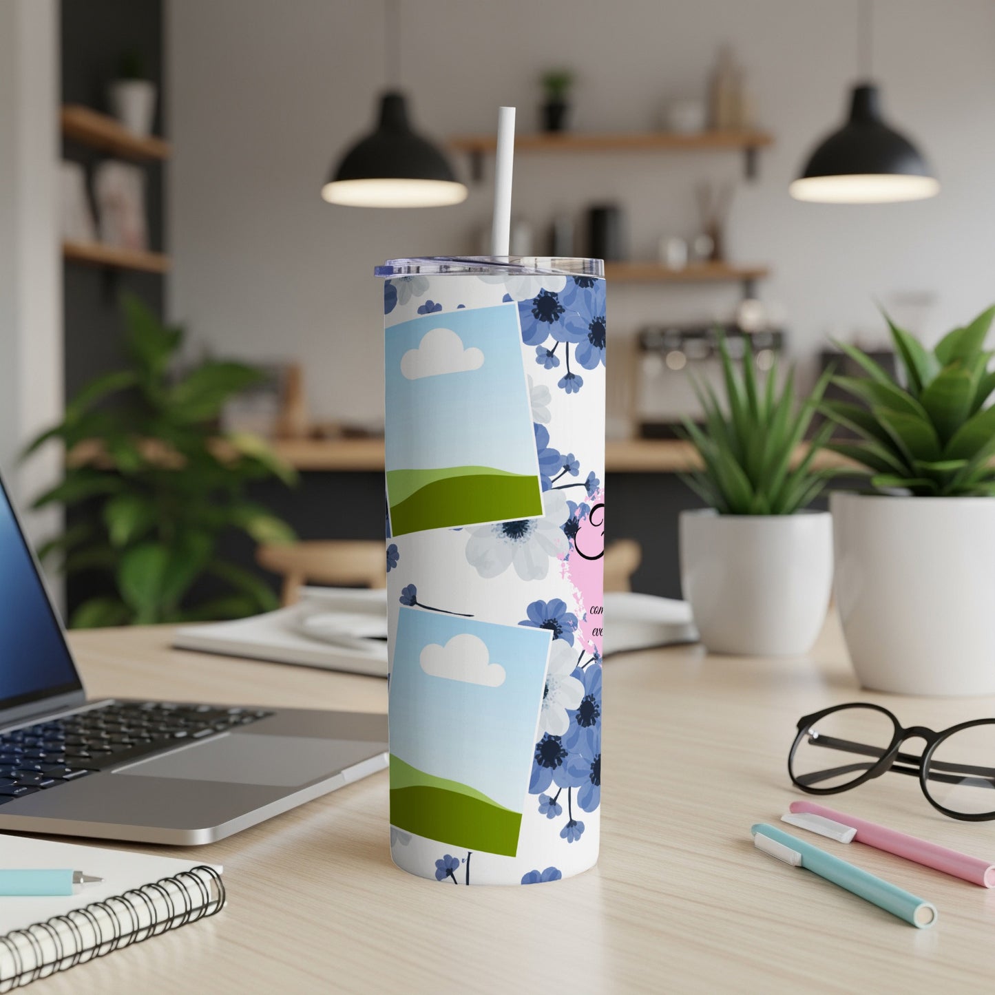 Tumbler with blue flowers, photos, and text on a desk with a laptop.