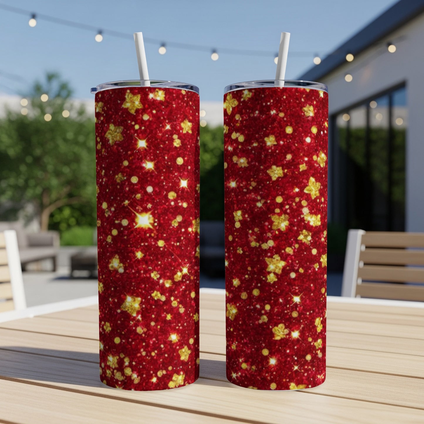 Two red glitter tumblers with gold star accents on a table outdoors.