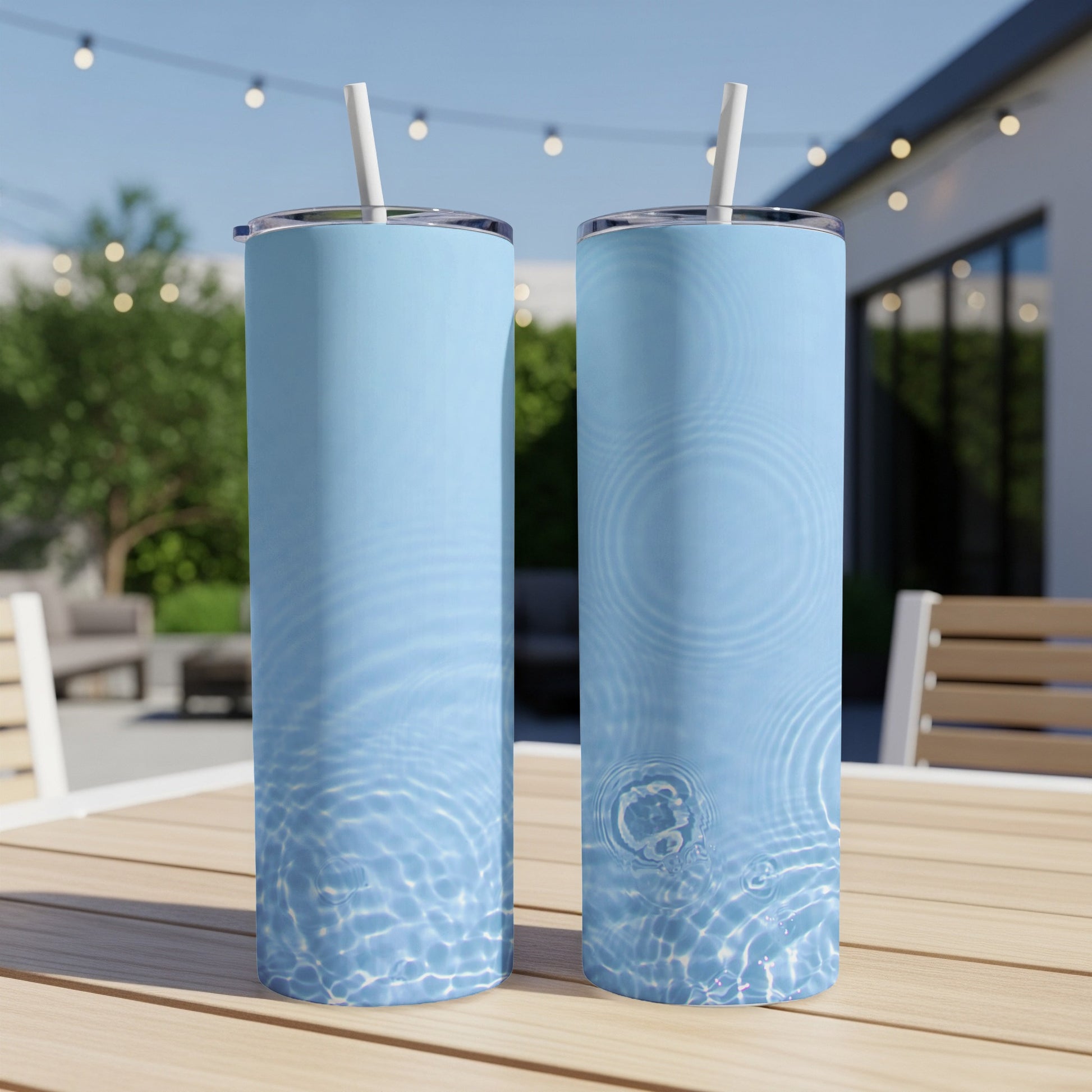Two light blue tumblers with water ripple pattern and straws on a table.